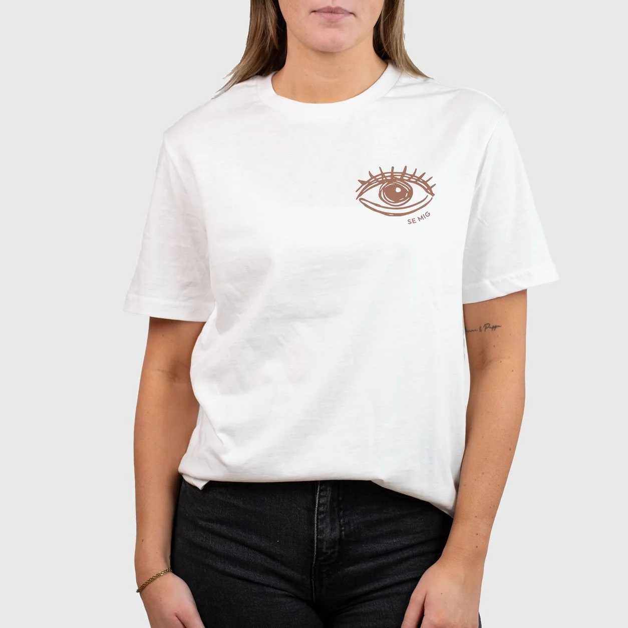 Kvinna i vit oversize t-shirt med ögonlogga på bröstet