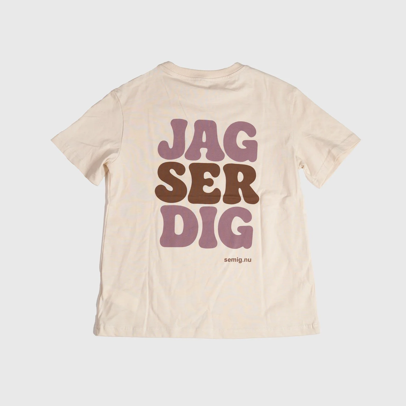 Sandfärgad oversize t-shirt i tjejmodell bakifrån med tryck ”Jag ser dig” i rosa och brunt
