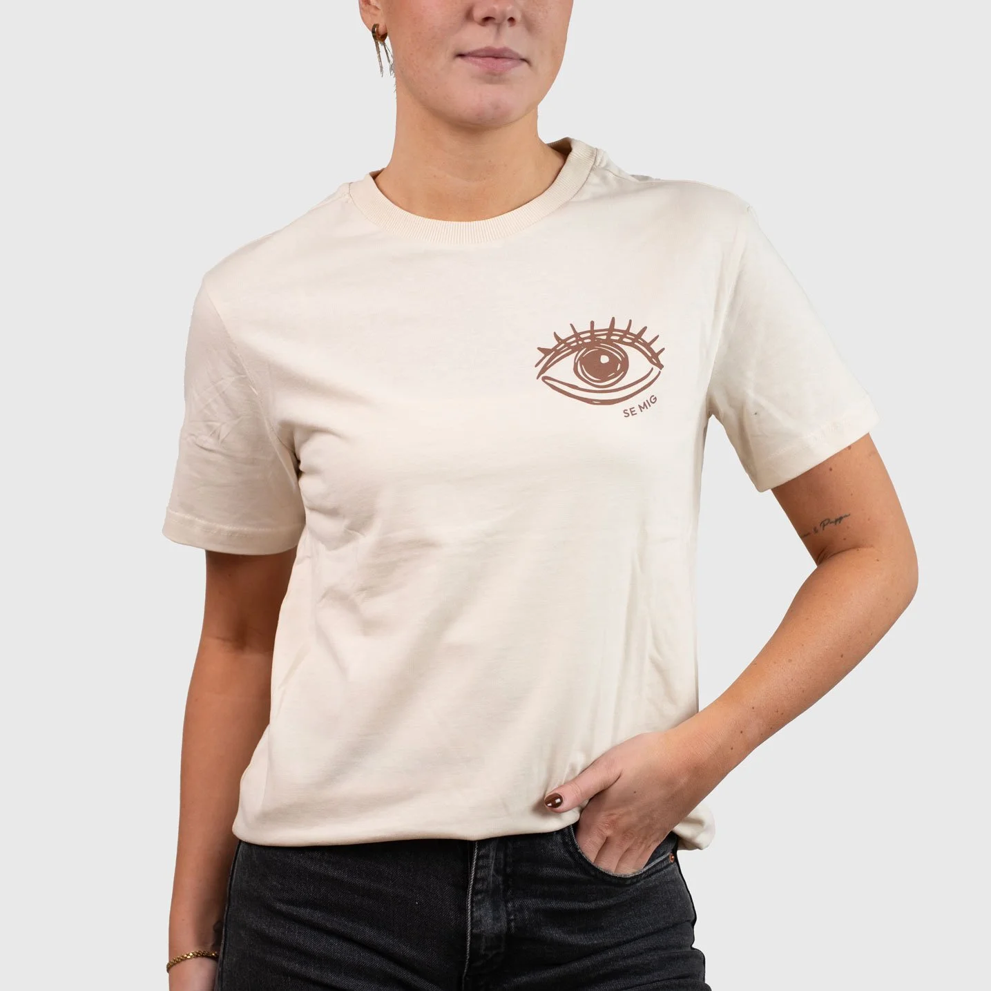 Kvinna i sandfärgad oversize t-shirt med ögonlogga på bröstet