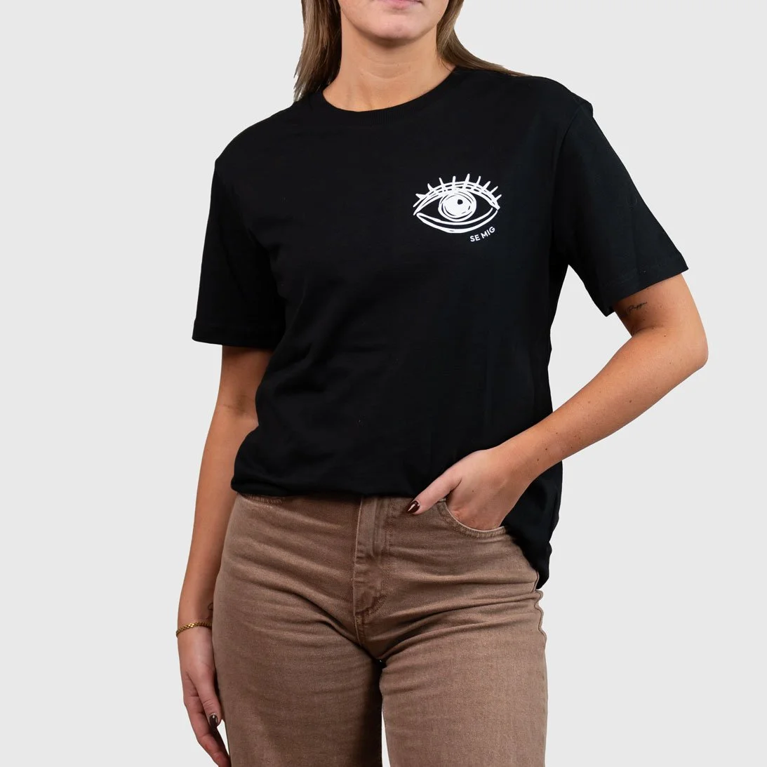 Kvinna i svart oversize t-shirt med ögonlogga på bröstet