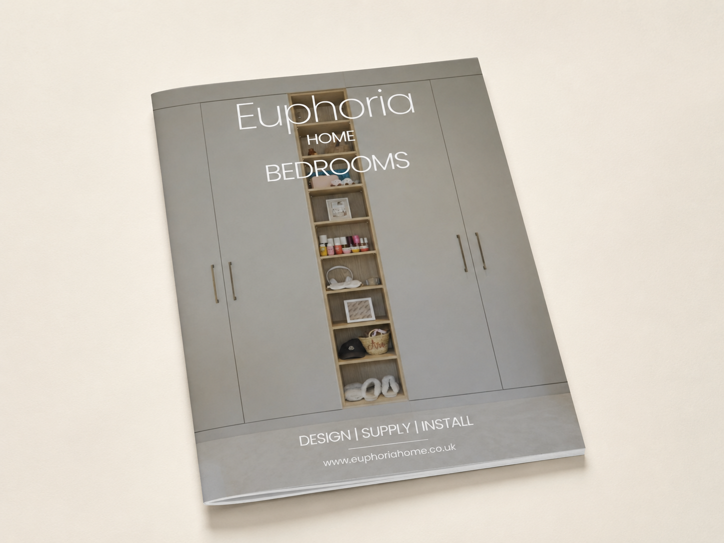 Brochure or catalog cover for Euphoria Home, featuring a large gray wardrobe with a central shelving compartment, displaying various decorative items and accessories. Text overlay includes 'Euphoria HOME BEDROOMS' and their website www.euphoriahome.co.uk, along with services 'DESIGN | SUPPLY | INSTALL'.