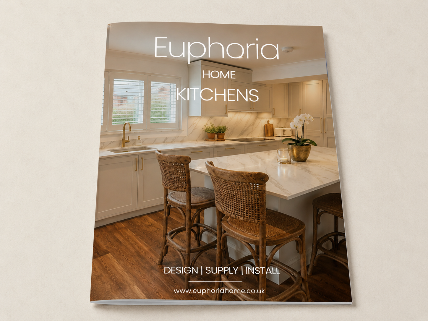 Brochure for Euphoria Home Kitchens showing a modern kitchen with white cabinets, a marble countertop, wooden chairs, and a window with shutters.