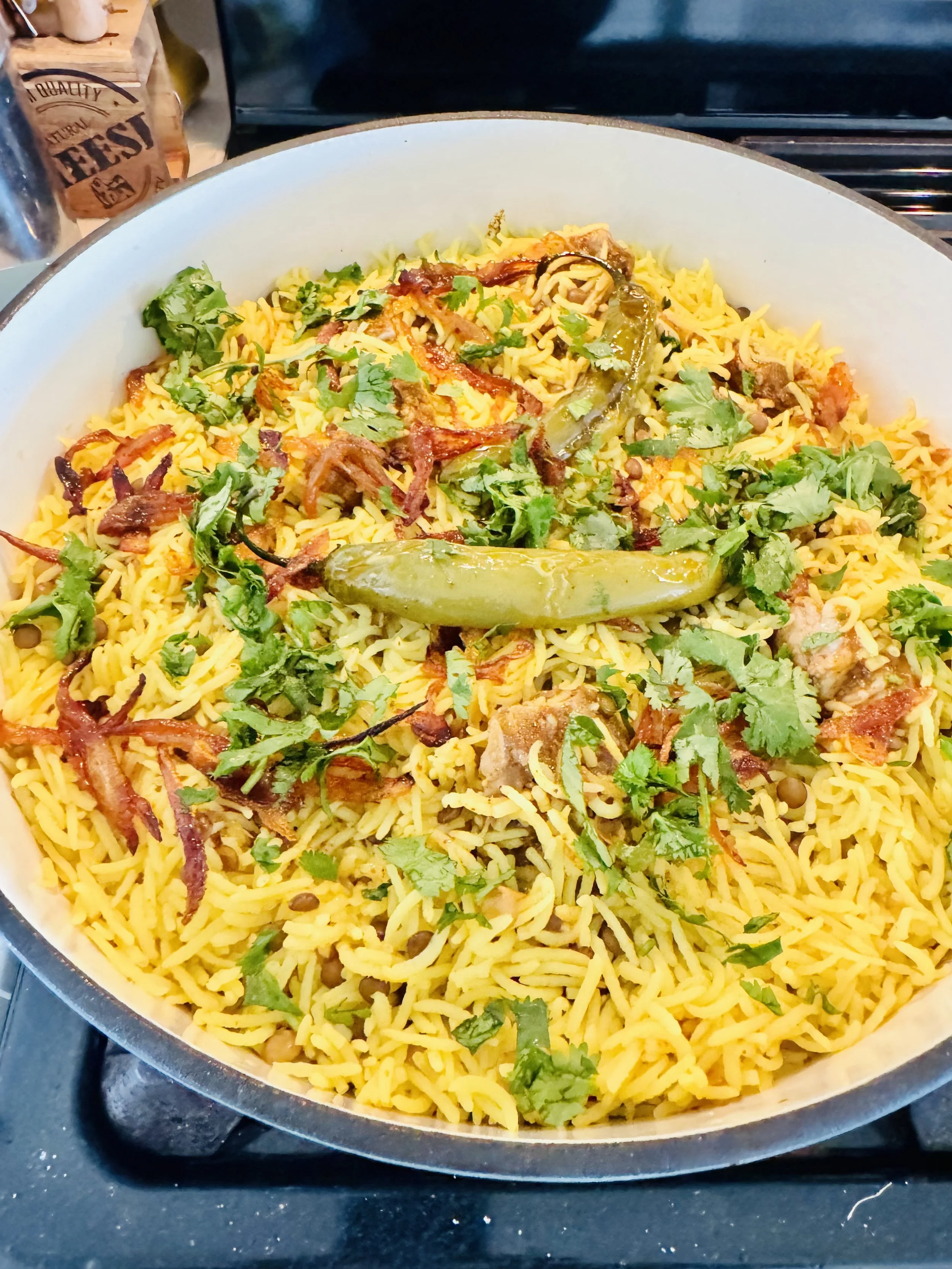 Dish of seasoned yellow rice topped with cilantro, crispy bacon, green chili peppers, and cooked onions.