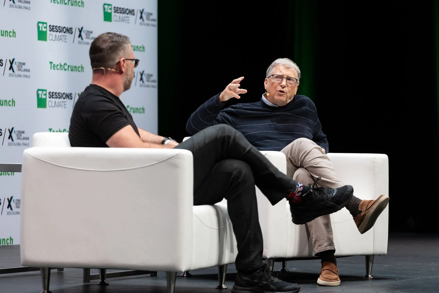 Two men sitting on white armchairs engaged in a conversation at a tech conference, with a backdrop displaying 'TechCrunch' and 'Sessions Climate' logos.