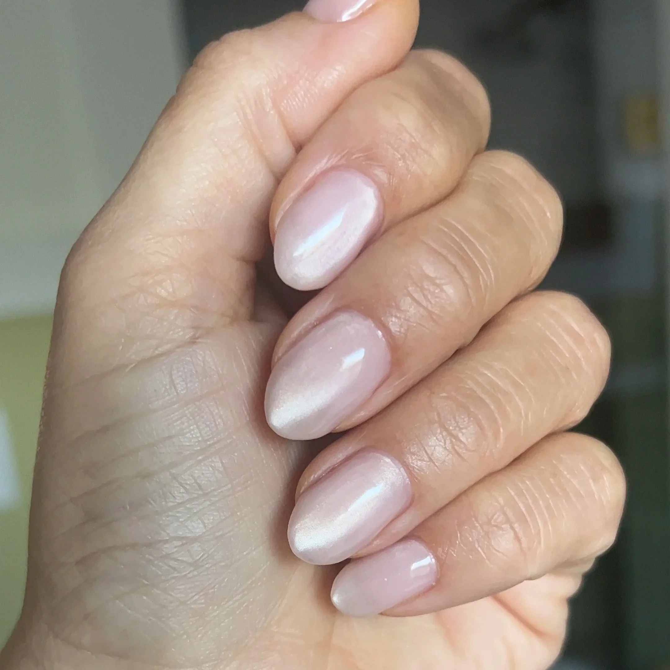 Manicured hand with Russian manicure and nude cat eye gel.