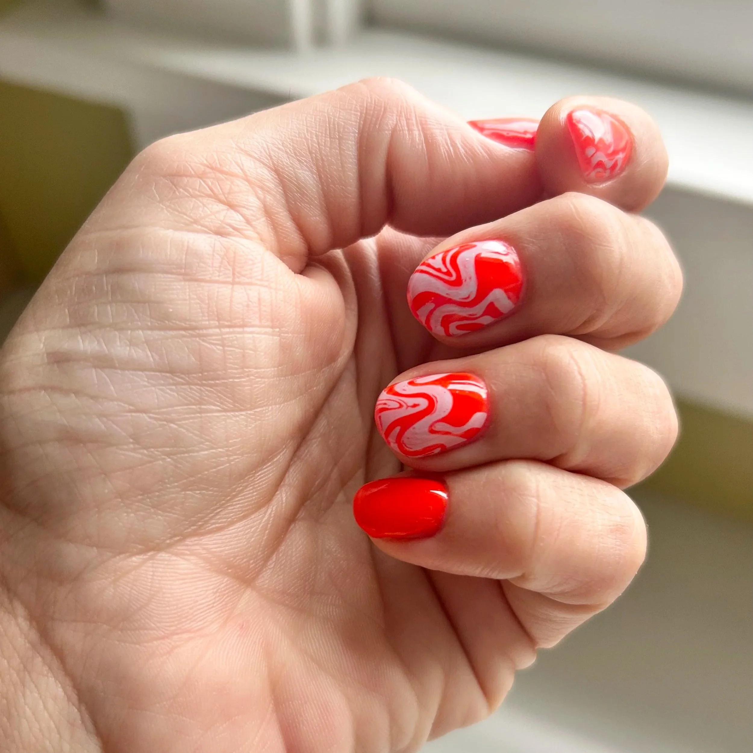 Red Gel manicure with blue swirls in Long Beach.
