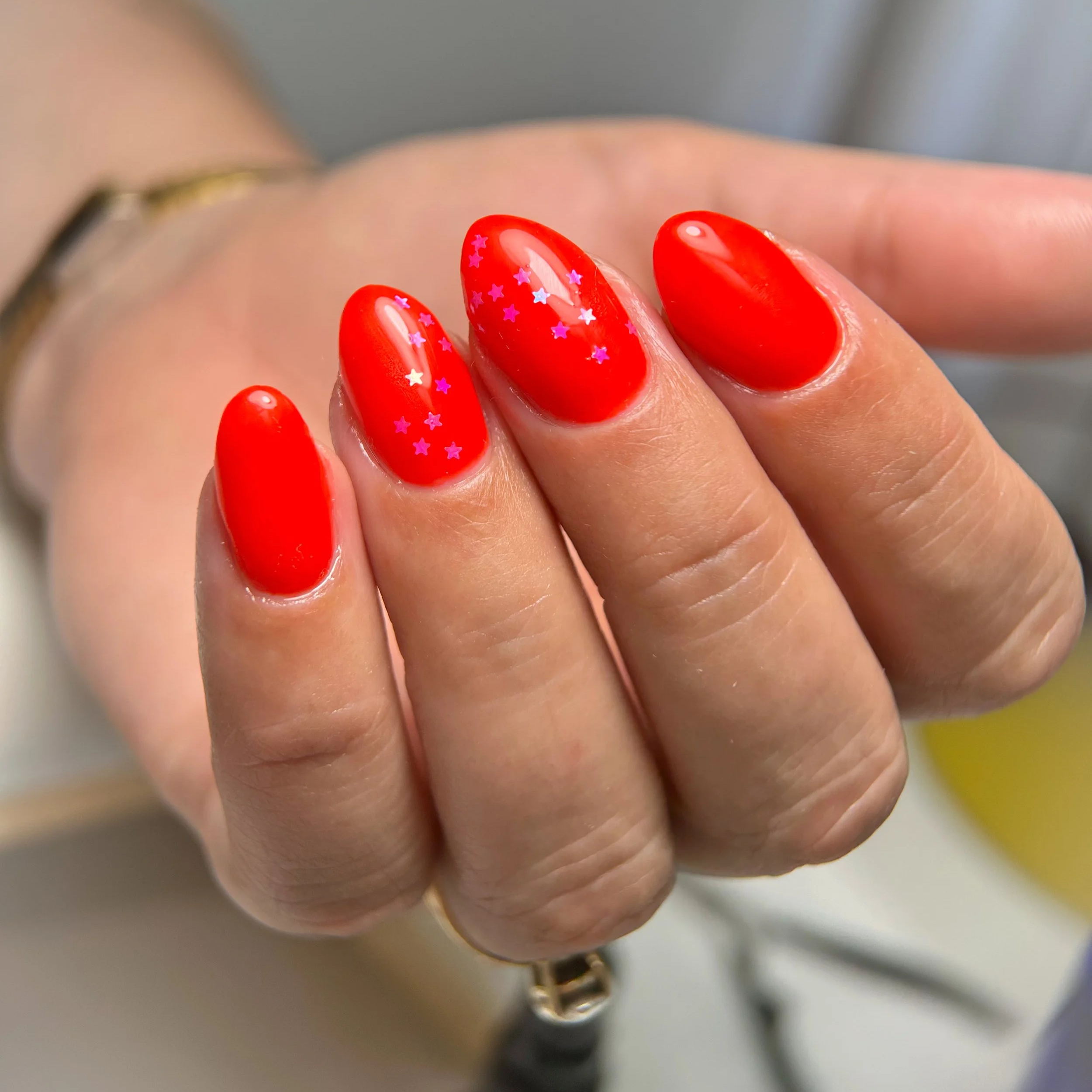Red structured manicure with tiny pink hearts encapsulated.