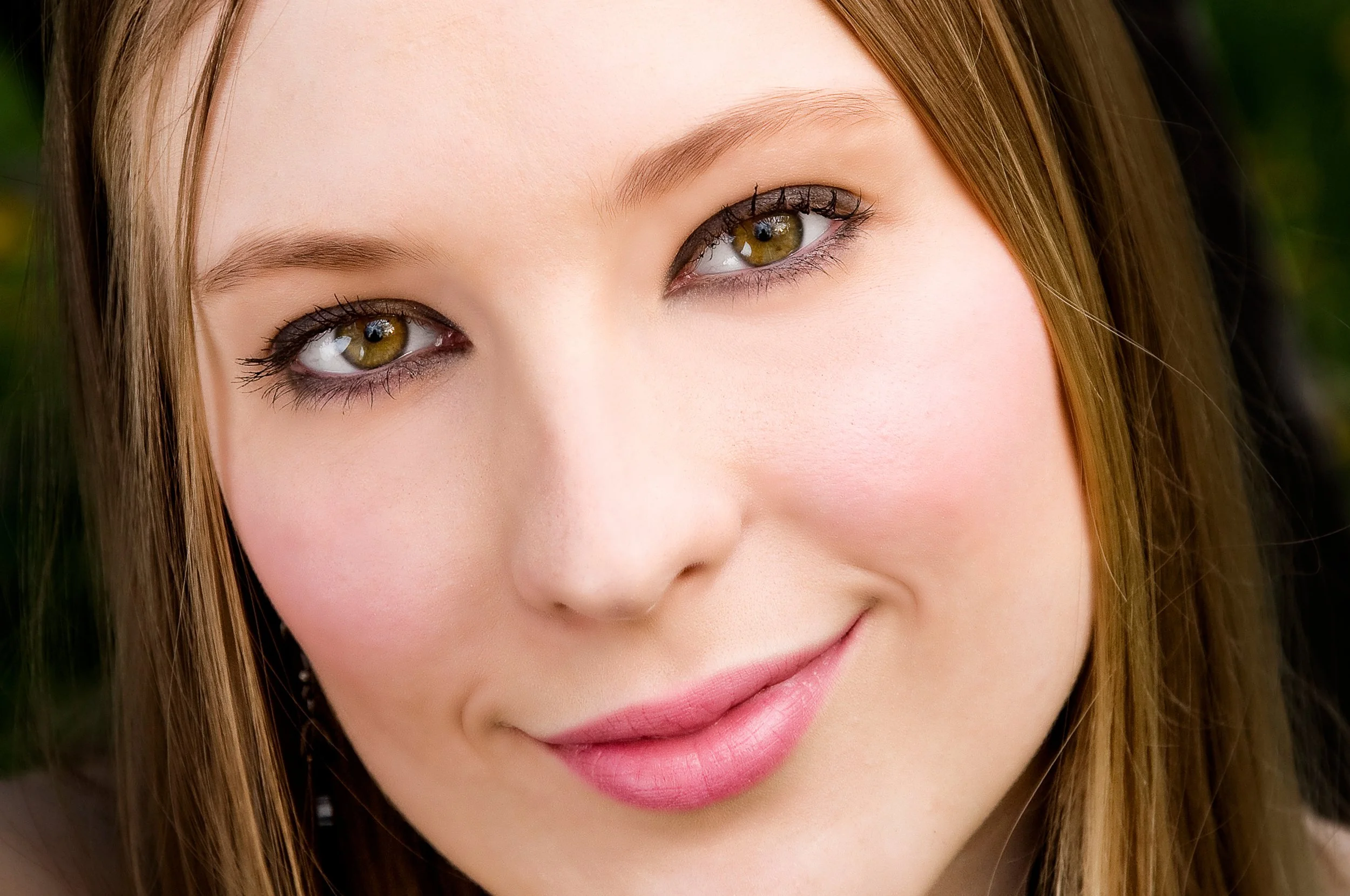 Close-up of a young woman's face showing her eyes, nose, and part of her mouth with perfect skin and straight brown hair.