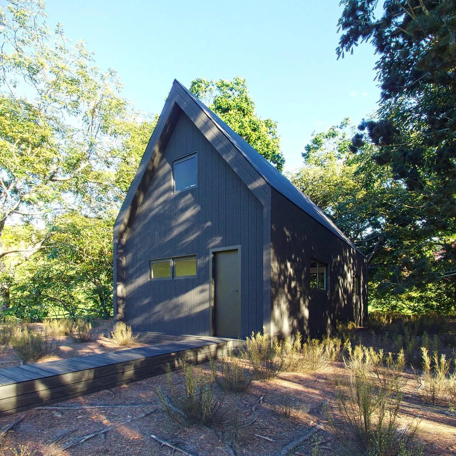 A modern dark gray house with a triangular roof, surrounded by trees and low bushes, under a clear blue sky.
