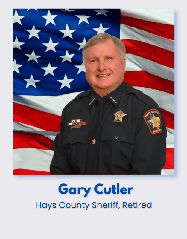 Retired Hays County Sheriff Gary Cutler in uniform, standing in front of an American flag background.