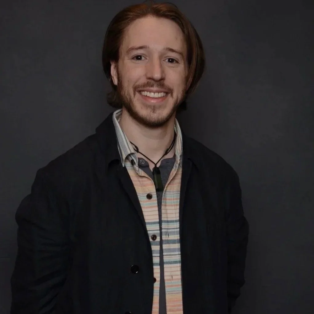 A man in a colorful shirt and black hat with a bird perched on his shoulder.