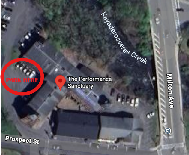 Aerial view of a parking lot at The Performance Sanctuary with a marked parking space labeled 'PARK HERE', adjacent to Prospect Street, near Kilkadeross Creek, and Milton Avenue in The Factory parking lot in Ballston Spa.