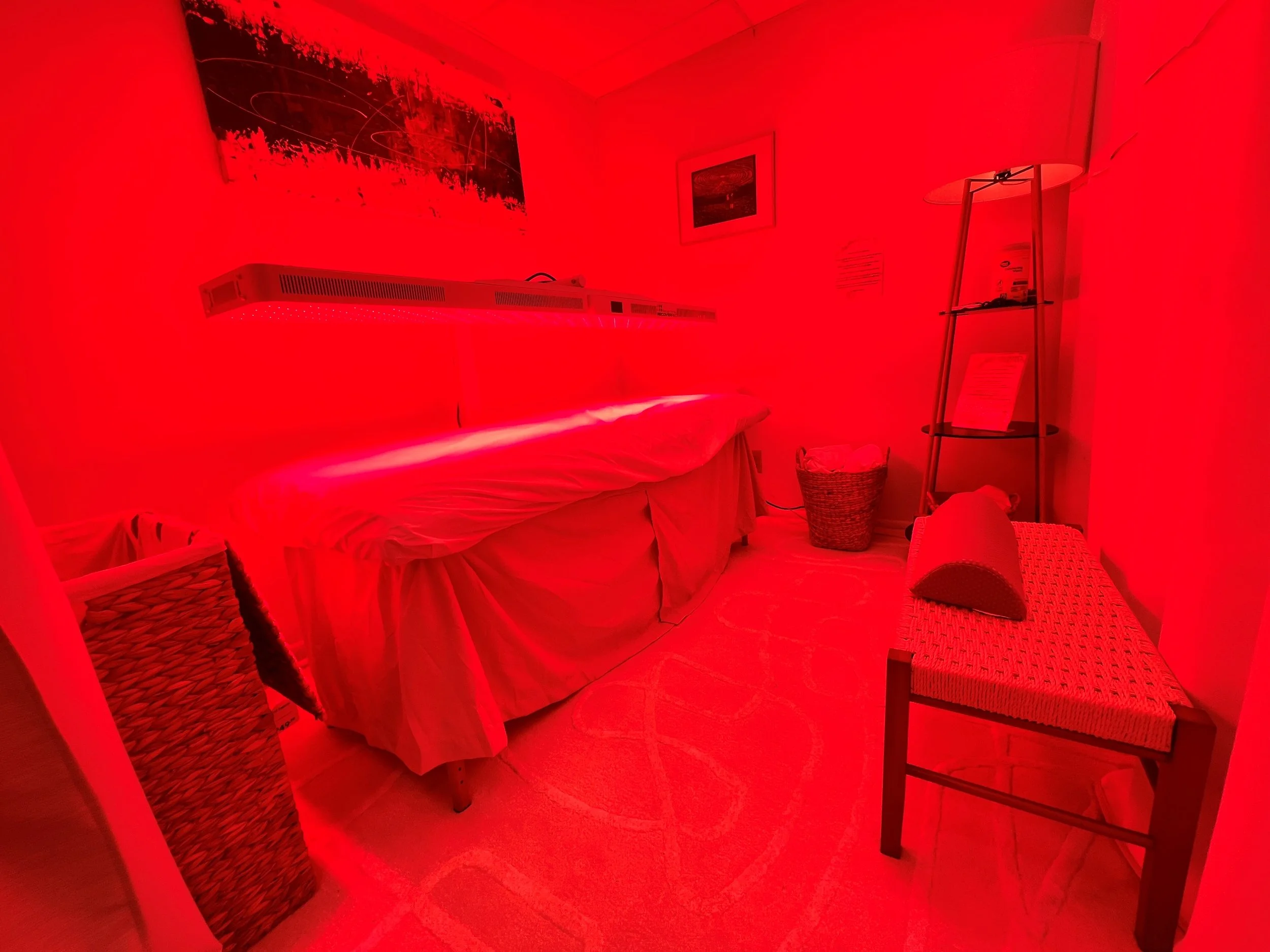 Room illuminated with red light showing a bed behind a folding decorative room divider.