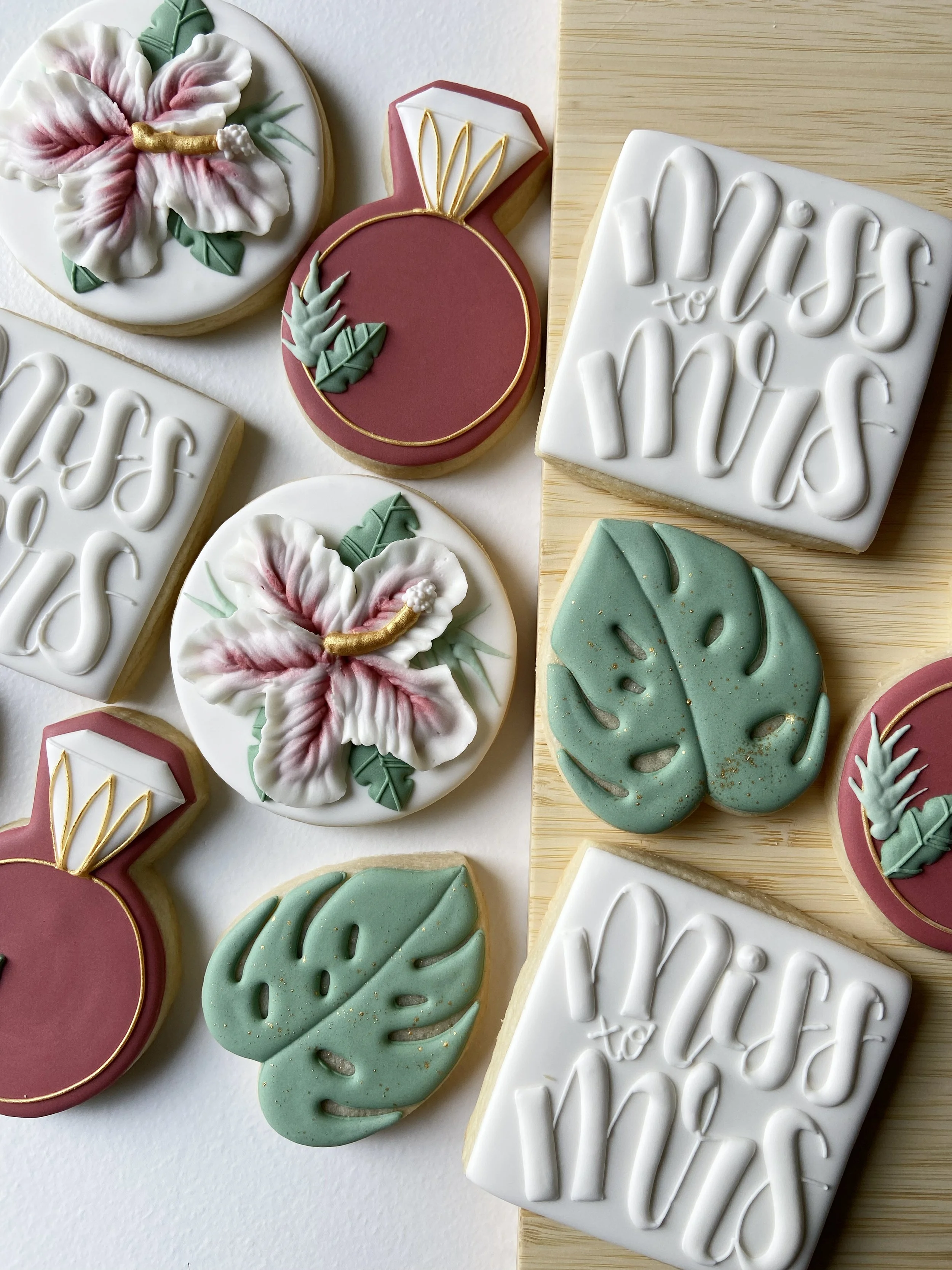 Decorative cookies with messages and tropical themes, including text 'miss to miss', flamingos, monstera leaves, and hibiscus flowers in pink, green, white, and gold accents.