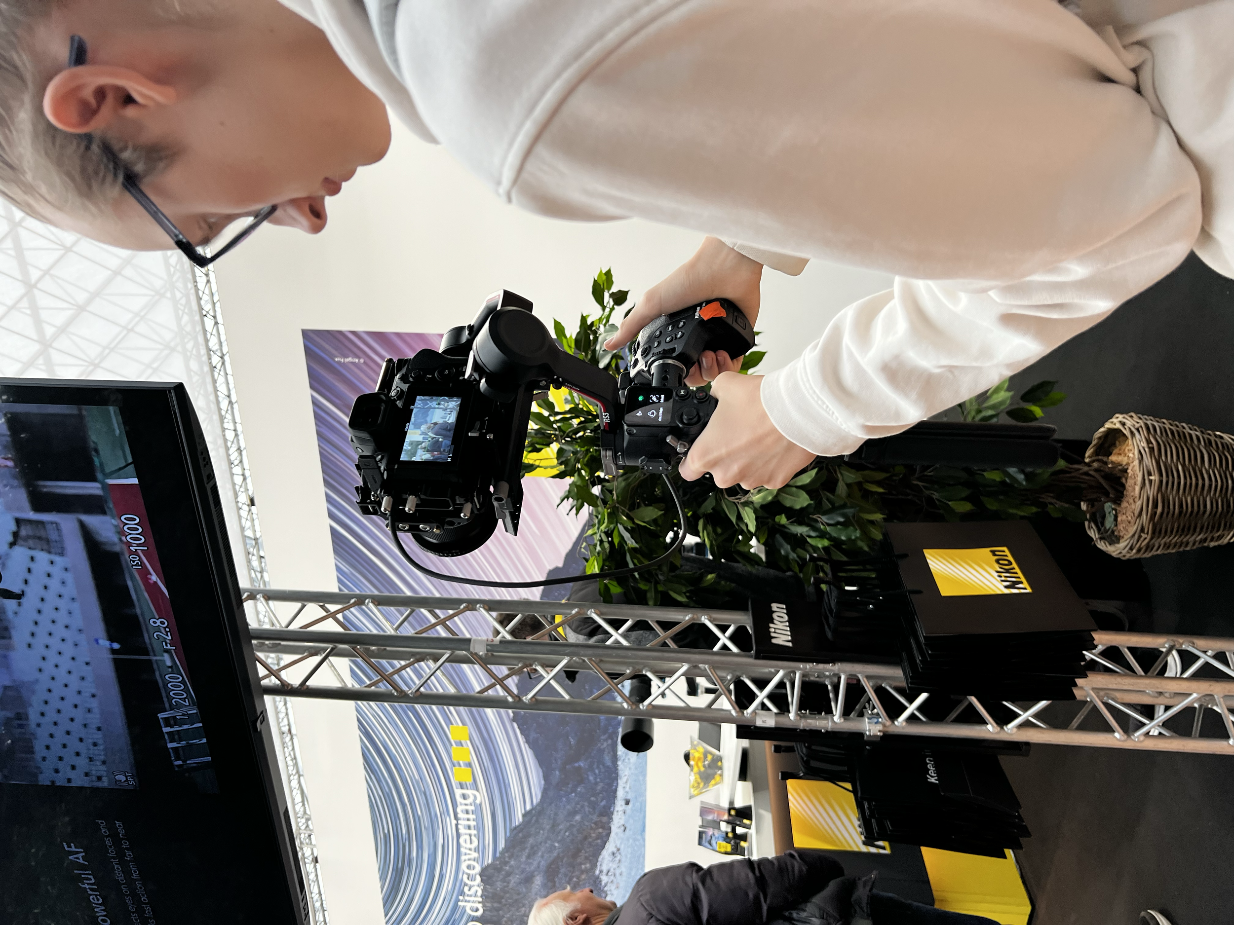 Person filmt mit einer Kamera bei einem Nikon-Stand auf einer Messe.