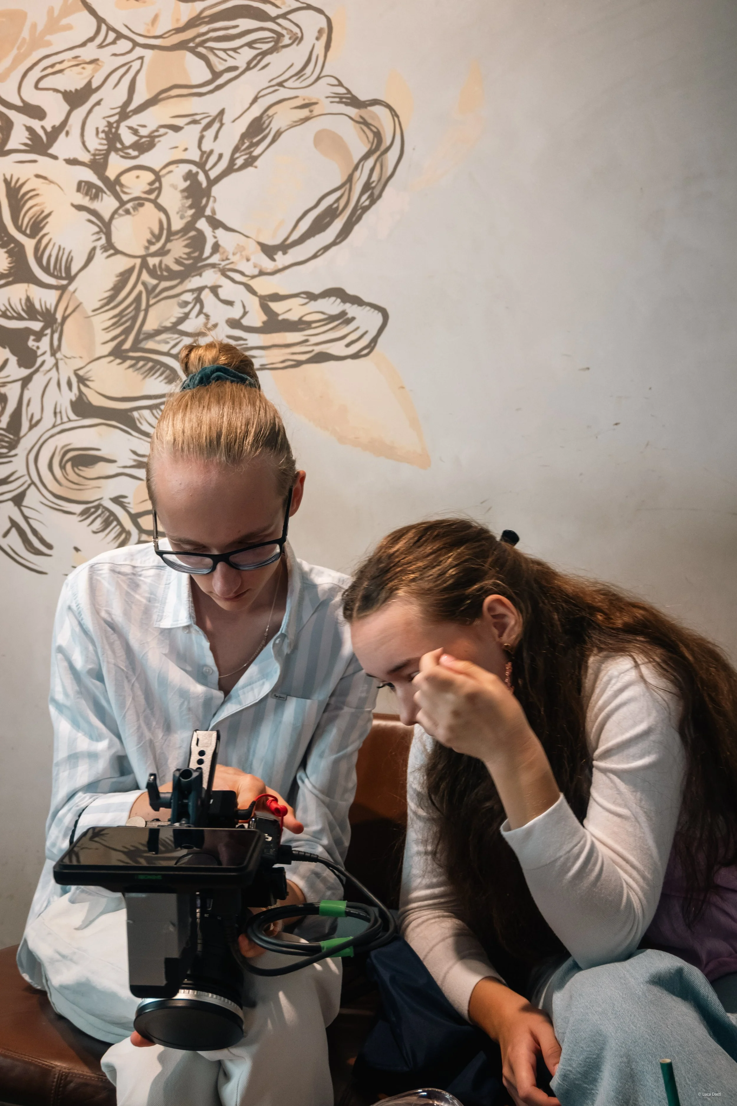 Zwei junge Frauen betrachten auf einem Tisch ein professionelles Filmsicherheitsgerät in einem Café, während sie beschäftigt und konzentriert aussehen.
