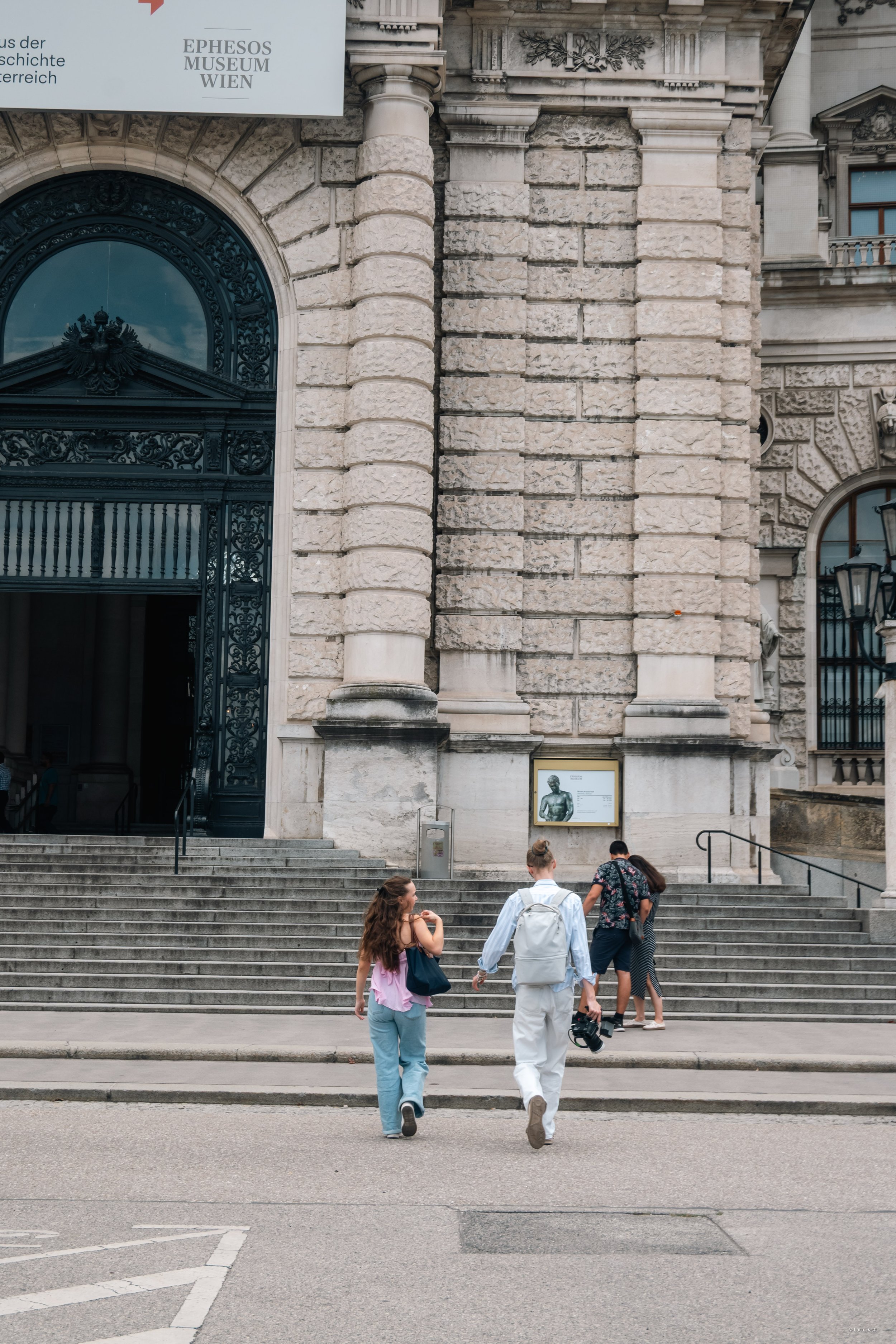 Menschen gehen die Treppe vor der Fassade des Ephesos Museum Wien hinauf.