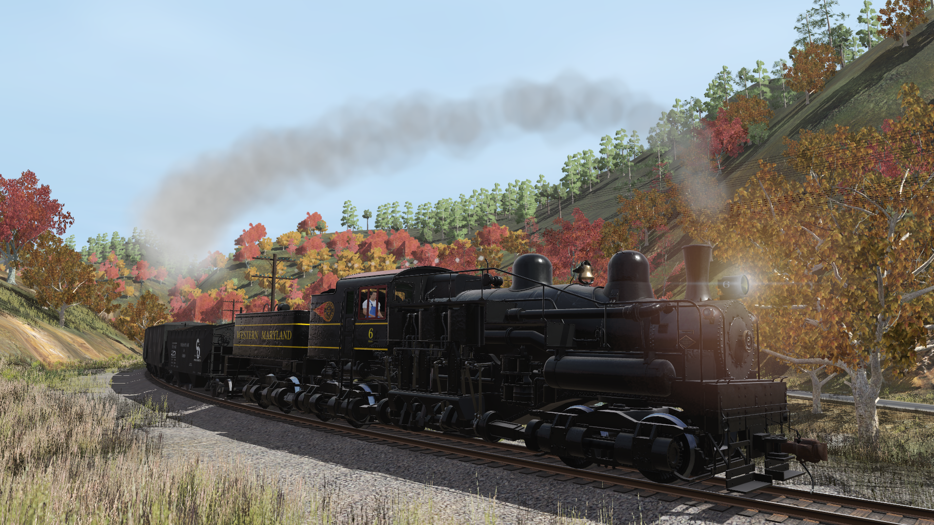 A black steam train labeled 'Western Maryland' moving through a scenic landscape with autumn-colored trees and a hillside with green and red foliage.