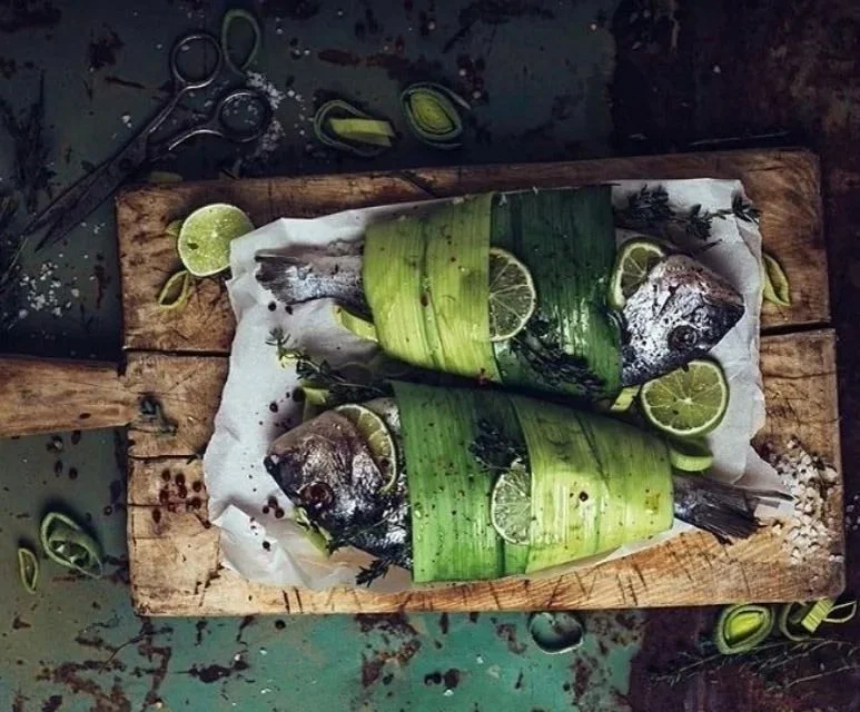 From above hands of unrecognizable woman rubbing aromatic spices into piece of raw meat over parchment paper