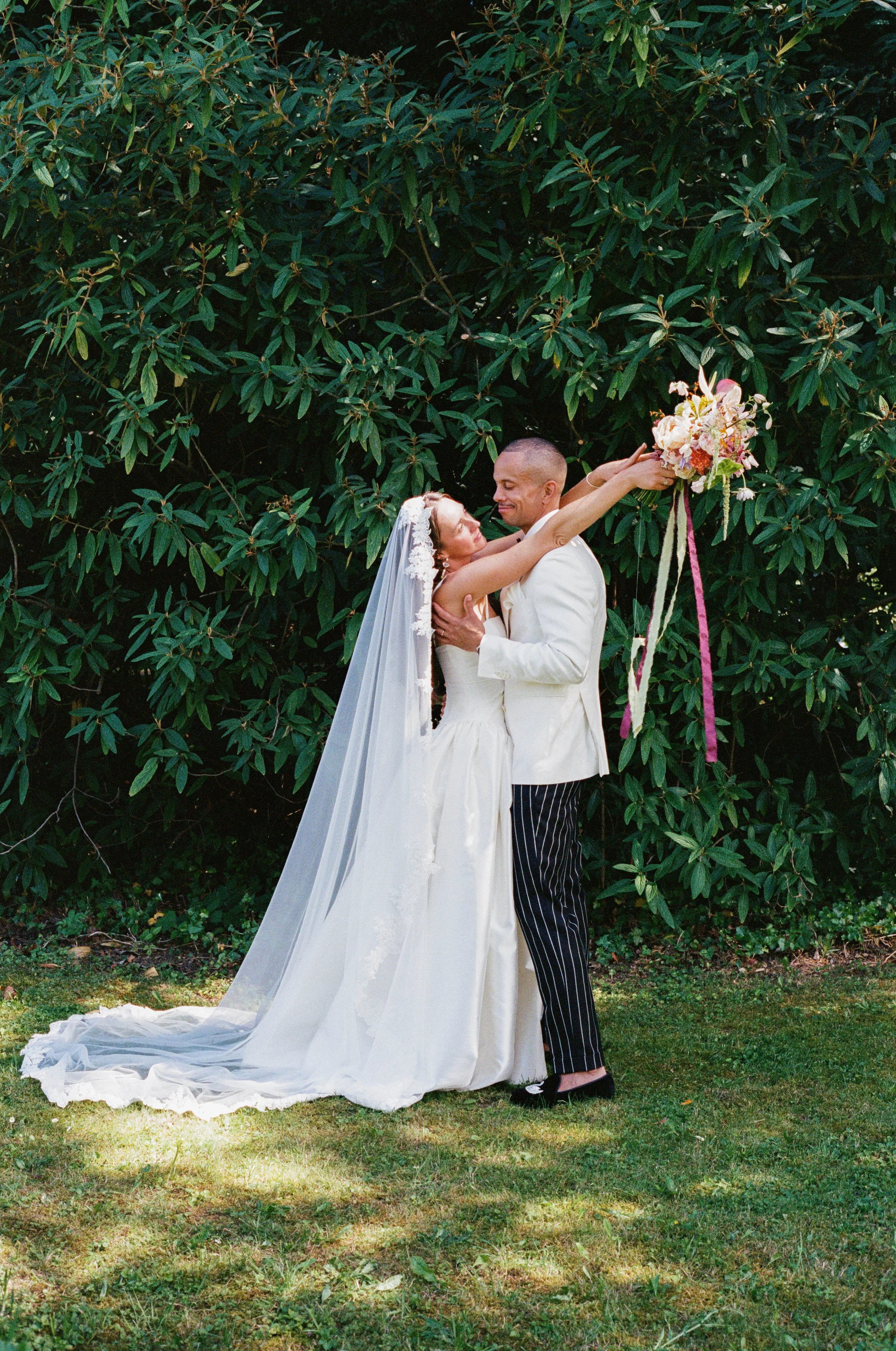 A bride holding a bouquet of pink and white flowers during a wedding ceremony outdoors.