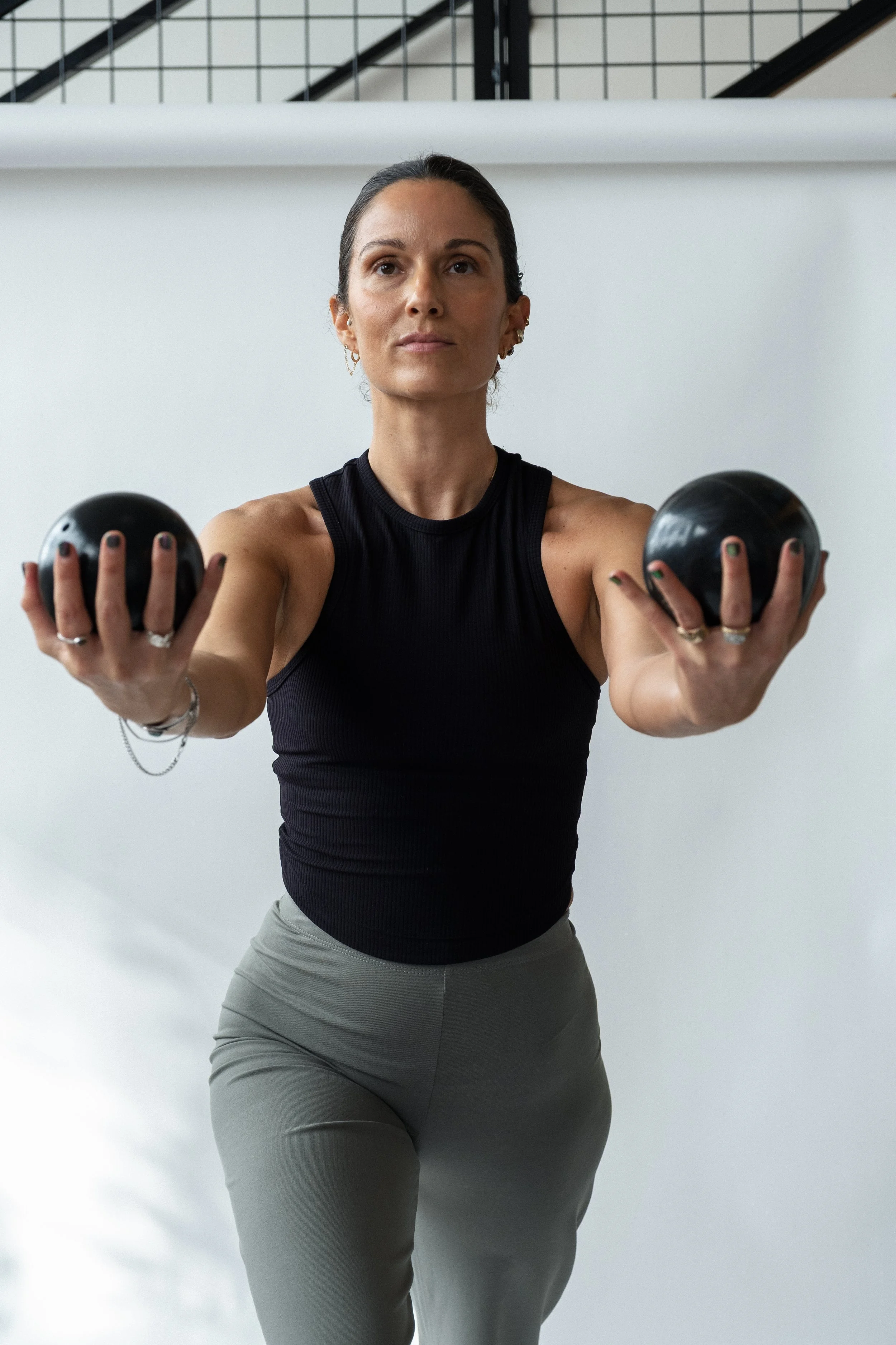A woman in workout attire holding two black weights out in front of her.