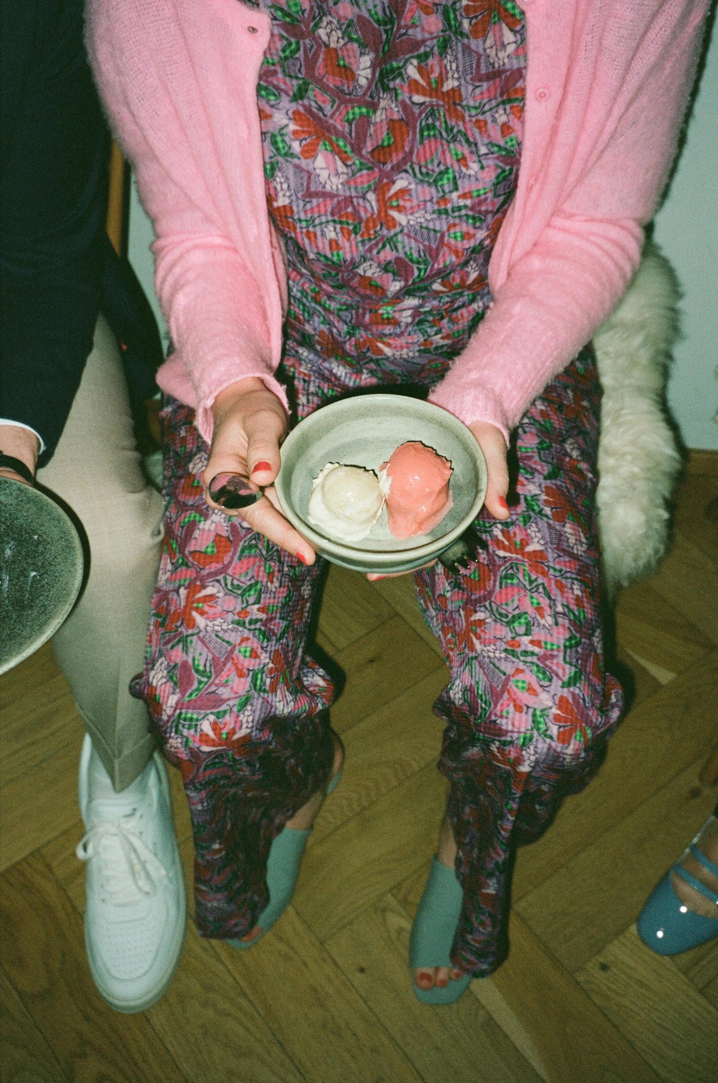 Person holding a bowl with two scoops of ice cream, one white and one pink.