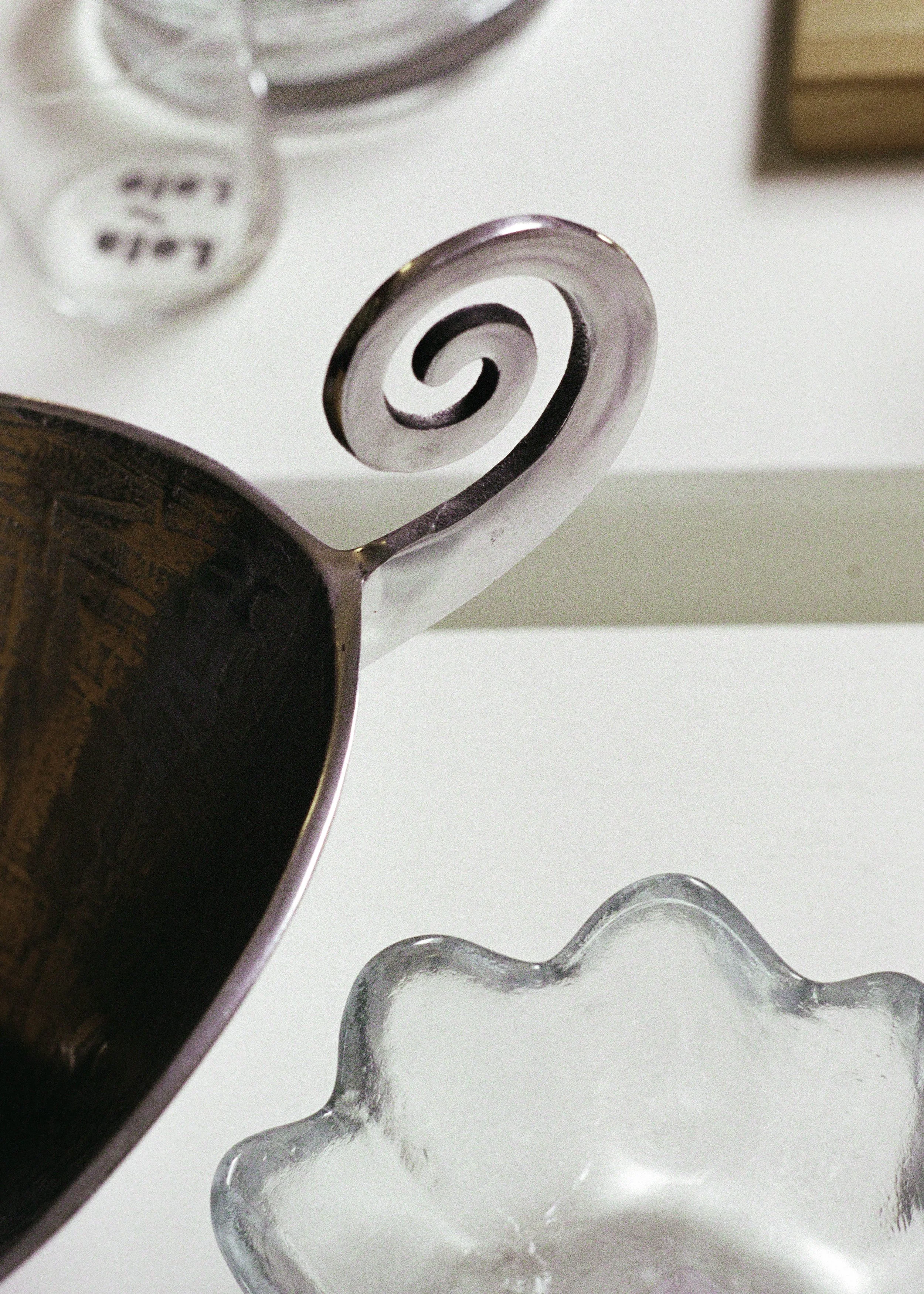 Close-up of a decorative glass handle and a glass dish on a white surface.
