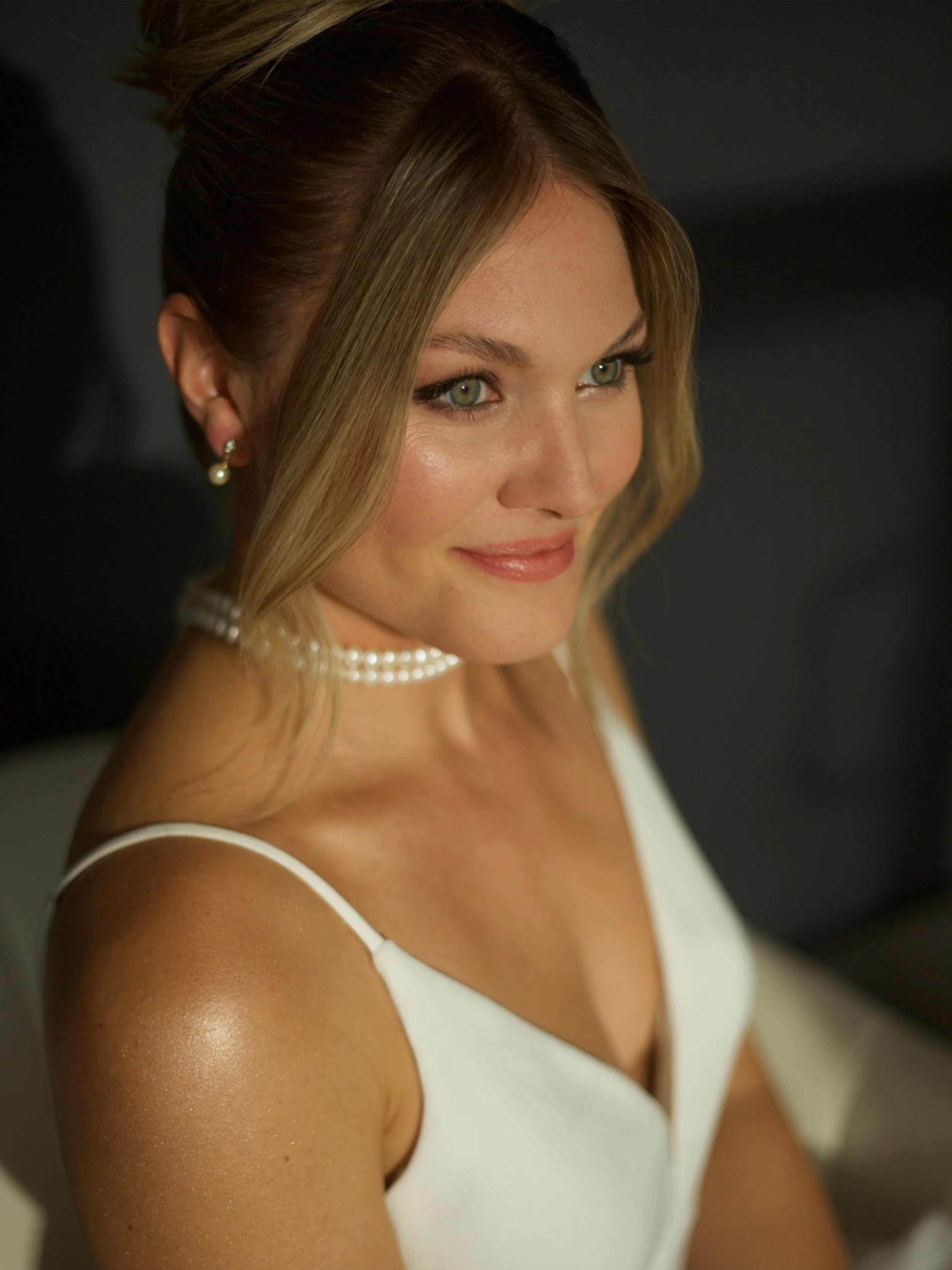 Textured bridal updo with soft tendrils for a romantic wedding look.