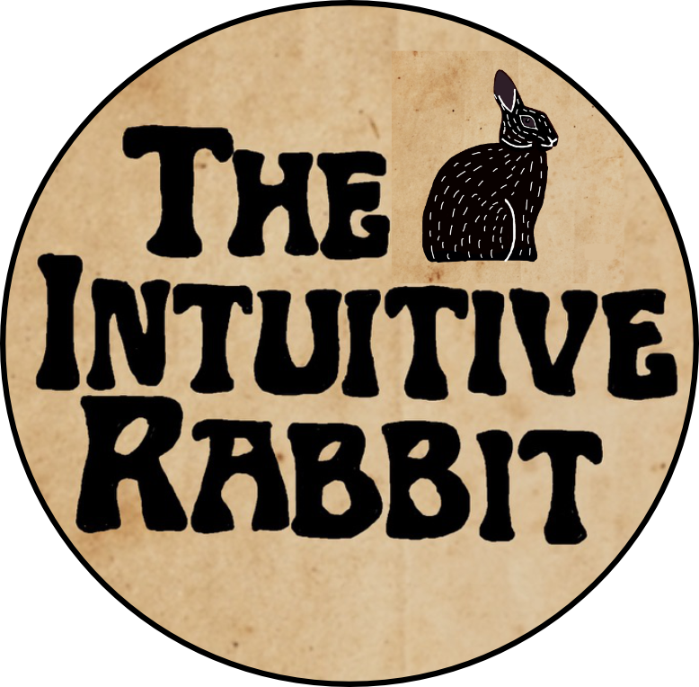 A circular logo with a beige background featuring black text that reads 'The Intuitive Rabbit' and an illustration of a black rabbit with white details in the top right corner.