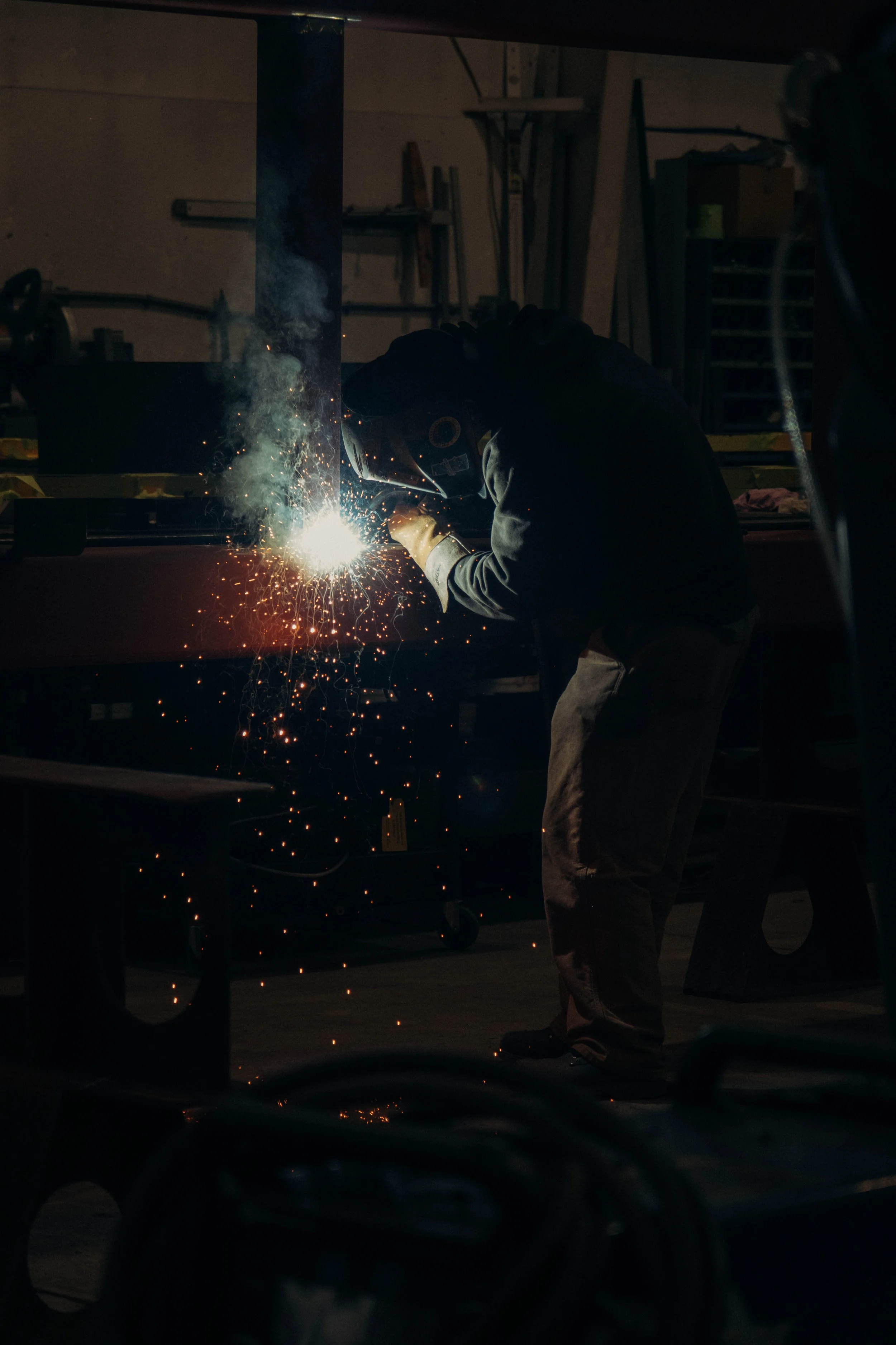 Person welding in a workshop, sparks flying as they work on a metal piece.