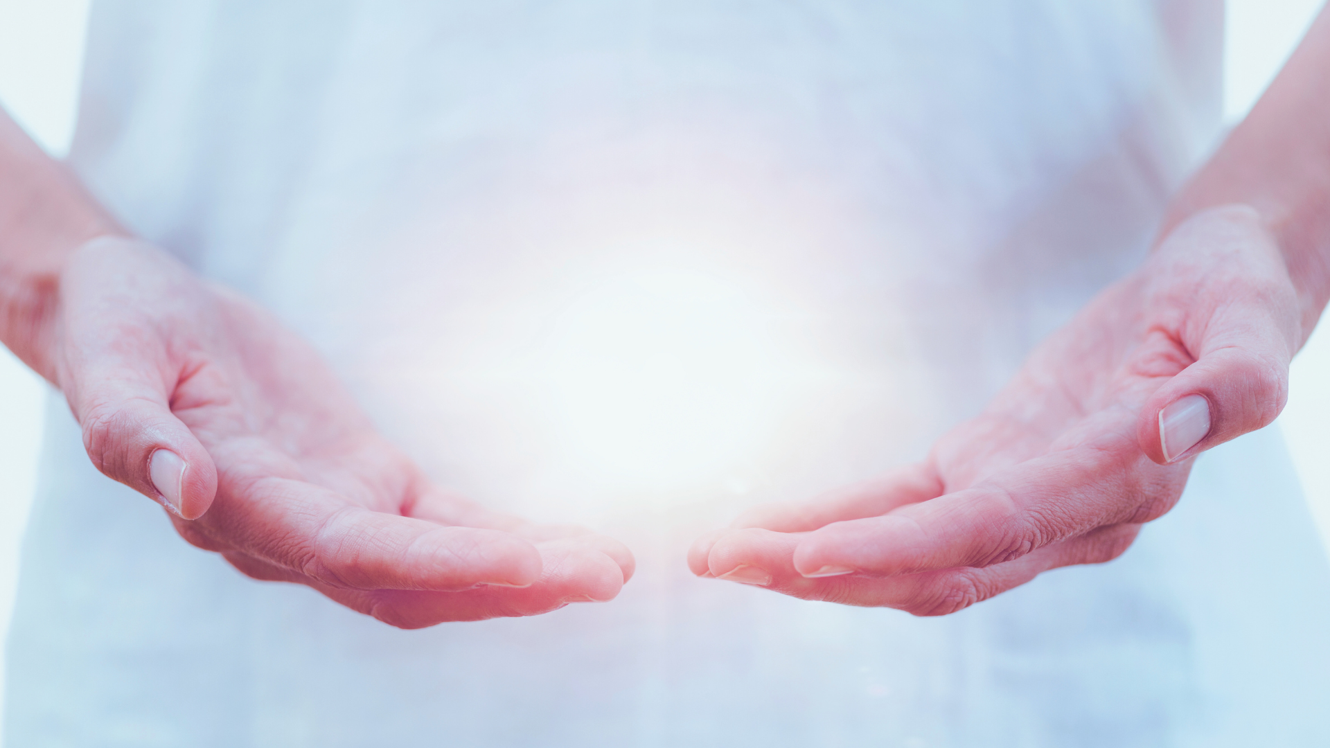 A pair of hands with palms up, seemingly holding or cradling a bright, glowing light
