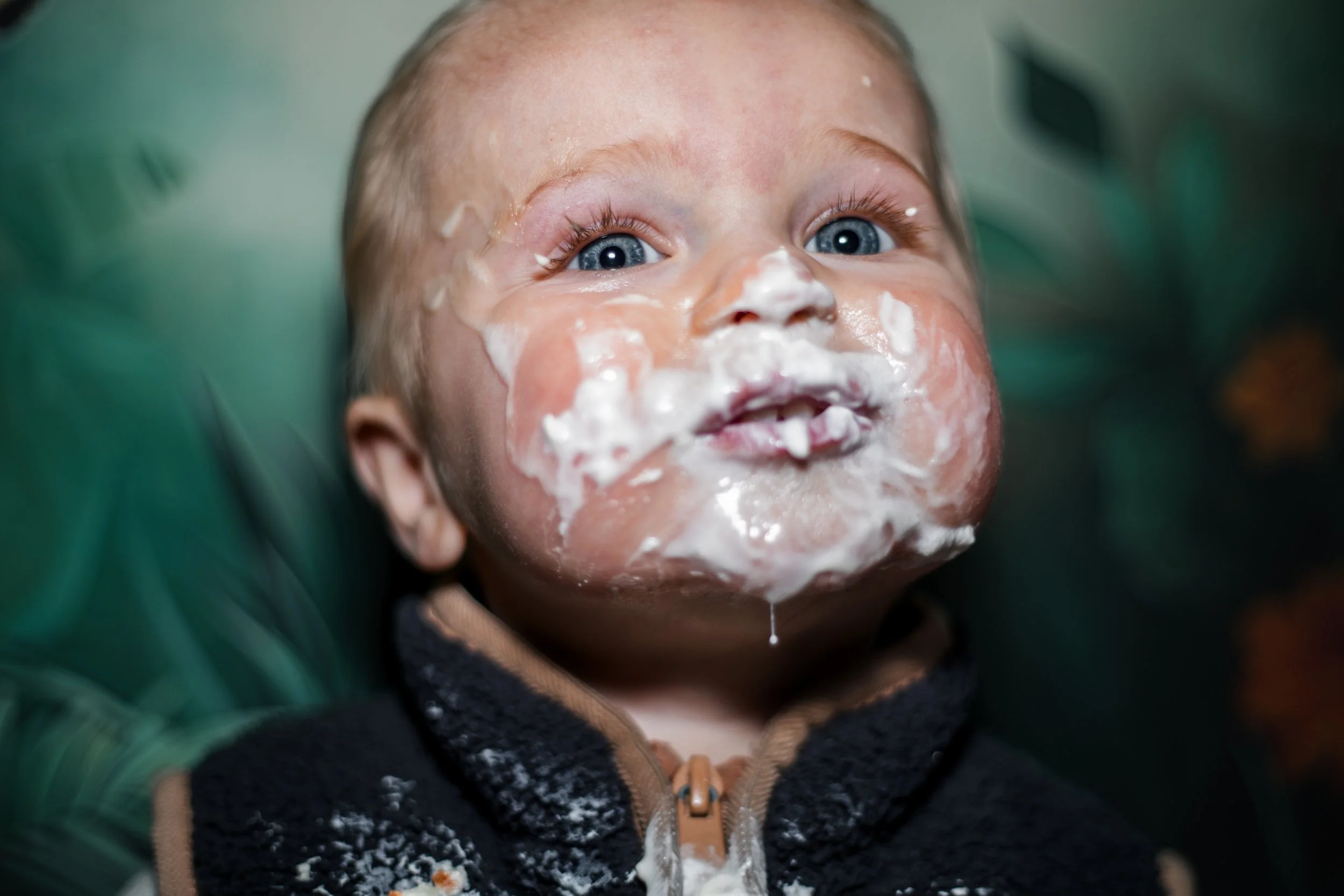 baby vier zijn eerste verjaardag met een enorme hoeveelheid slagroom om zijn mond