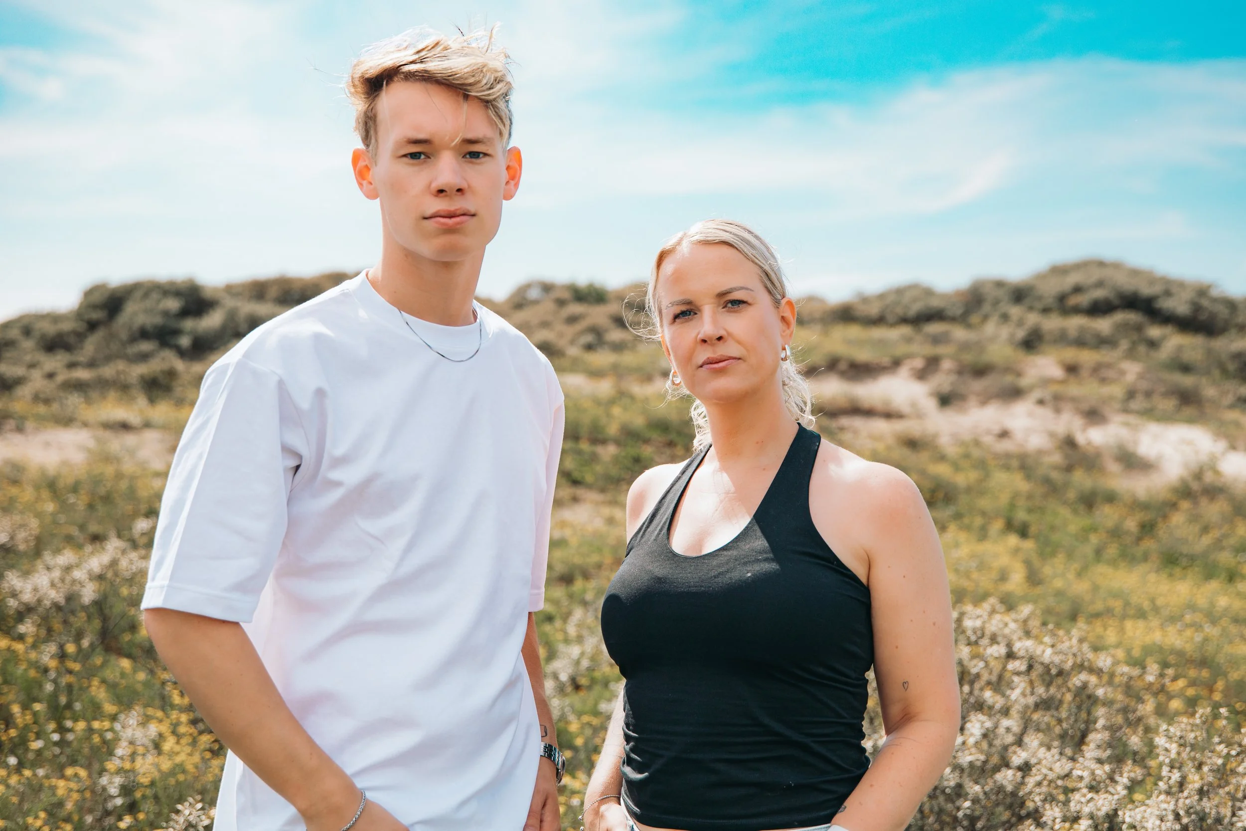 Twee vrouwen staan buiten in een landschap met lage struiken en een heldere blauwe lucht, beiden kijken serieus naar de camera. Foto door SteefClicks / Steef