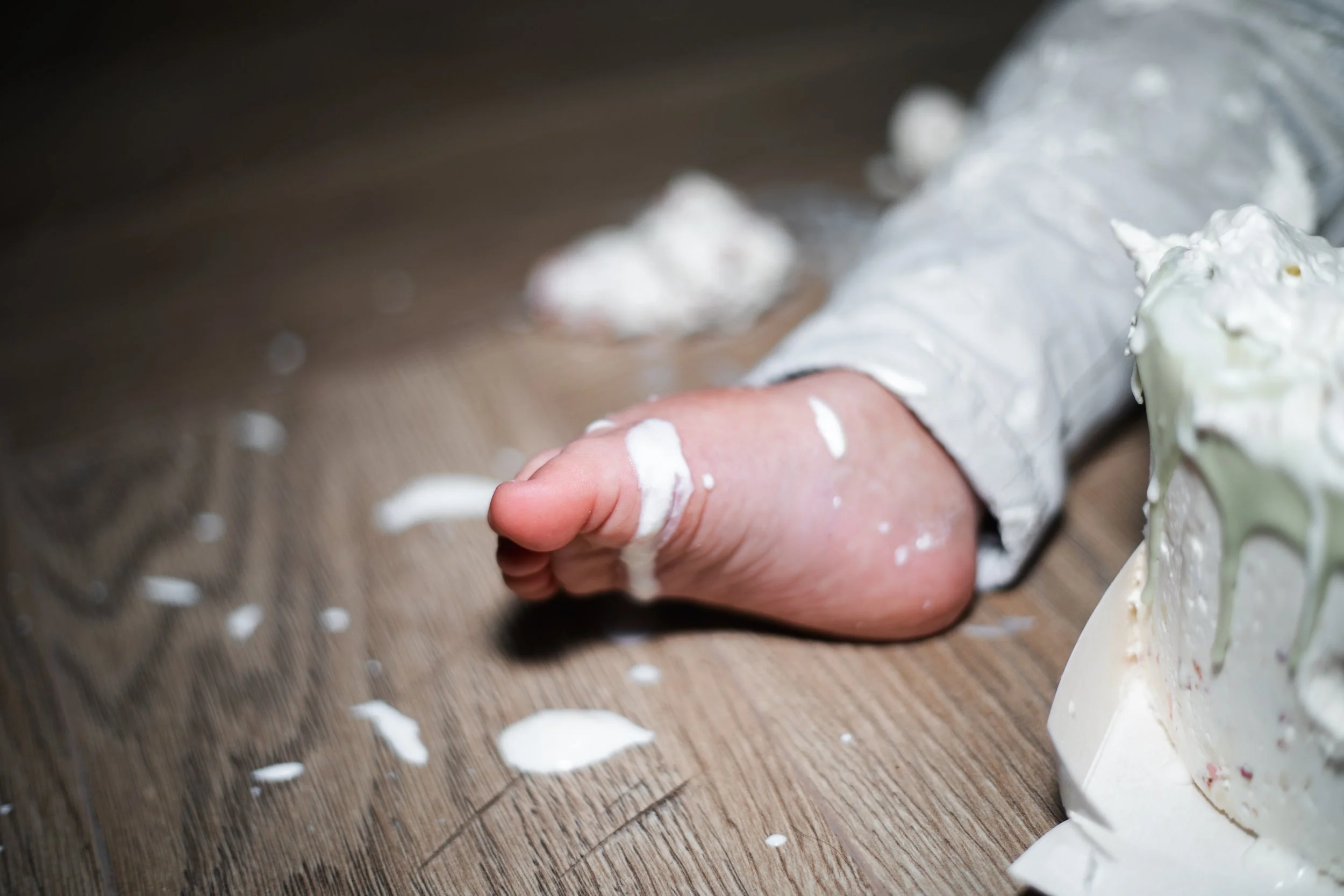 kindje zit onder de taart en slagroom tijdens  een cakesmash fotoshoot