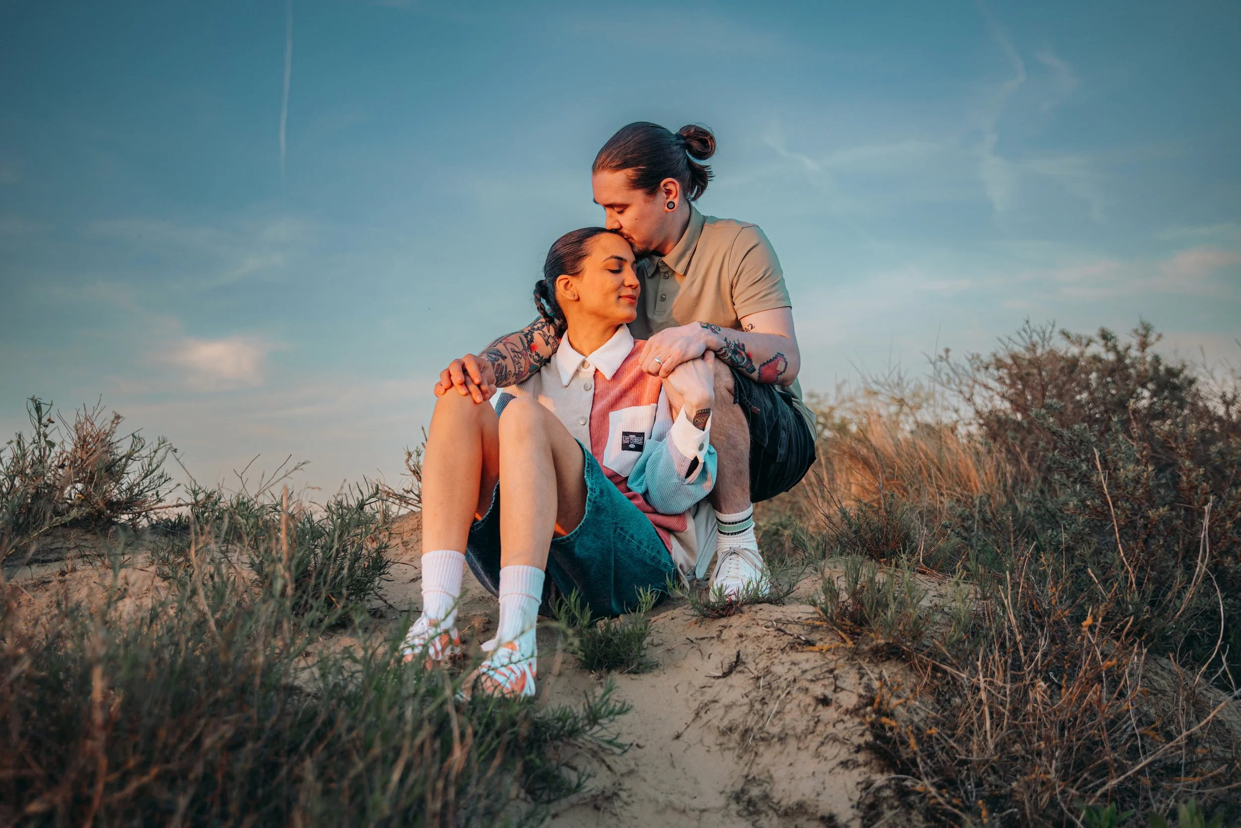 Twee mensen in een veld bij zonsondergang, een man die een vrouw die op zit kust.