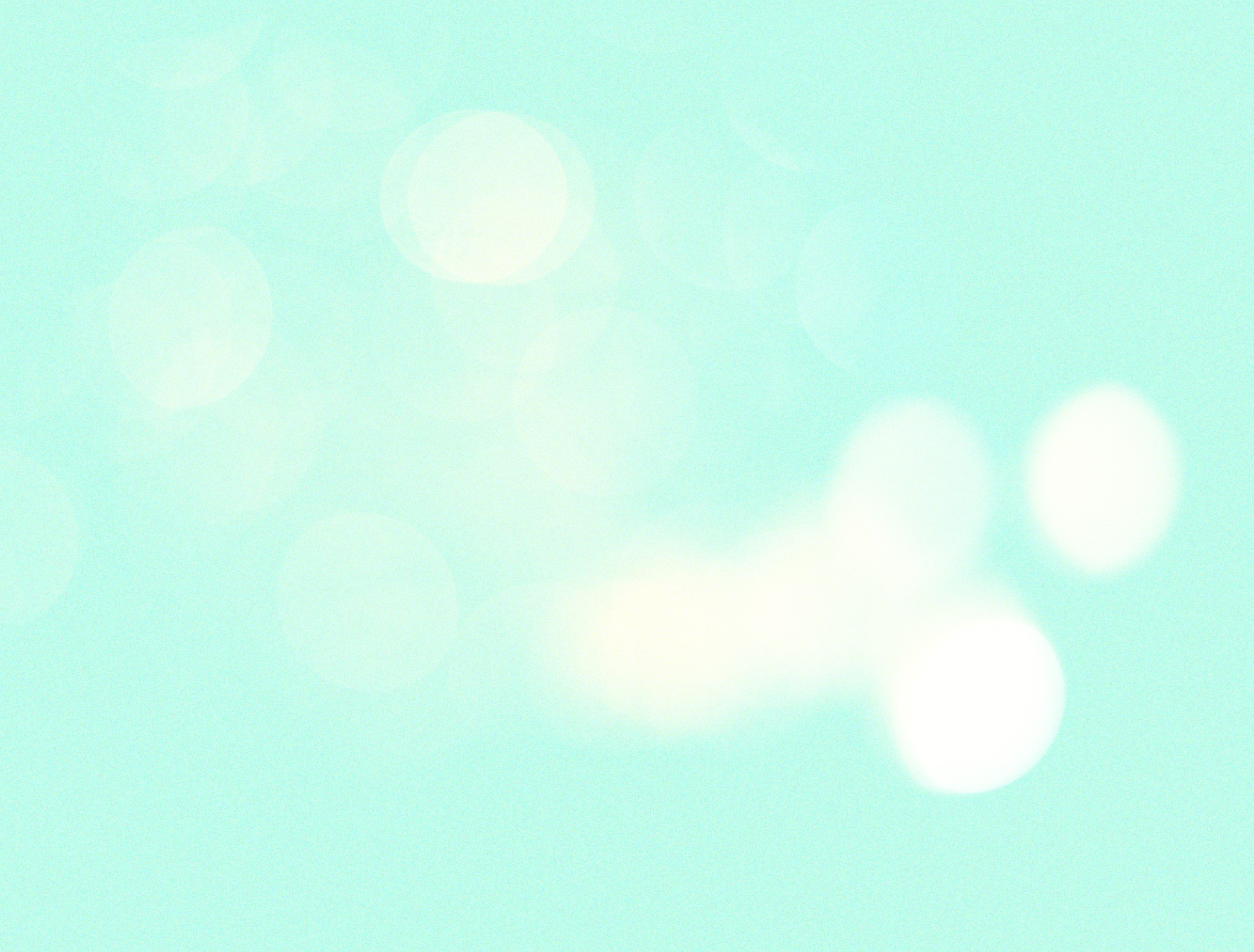 A soft blue-green bokeh background with blurred circular light spots.
