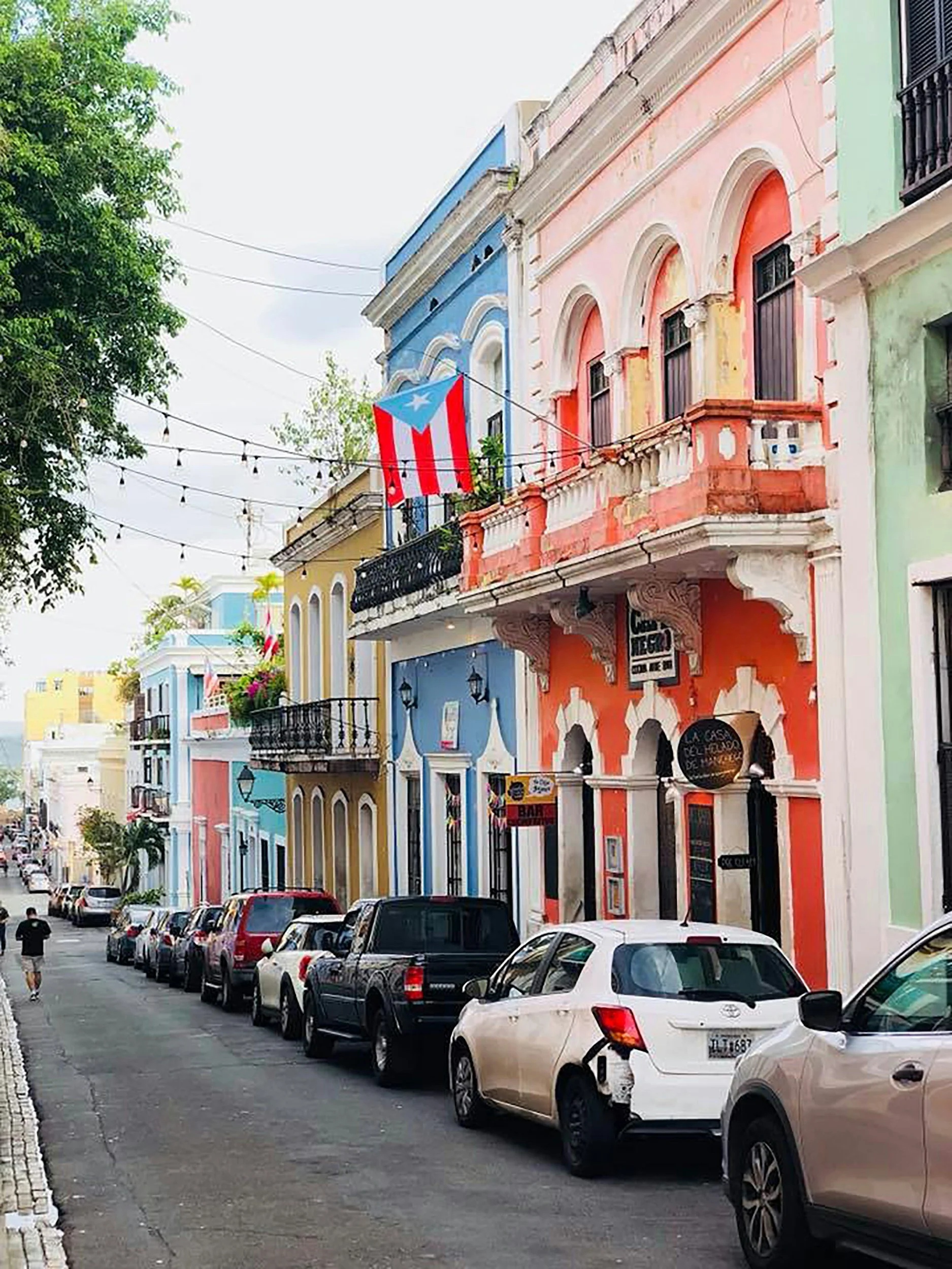 Colorful buildings on a street in Puerto Rico with a Puerto Rican flag hanging above the street.