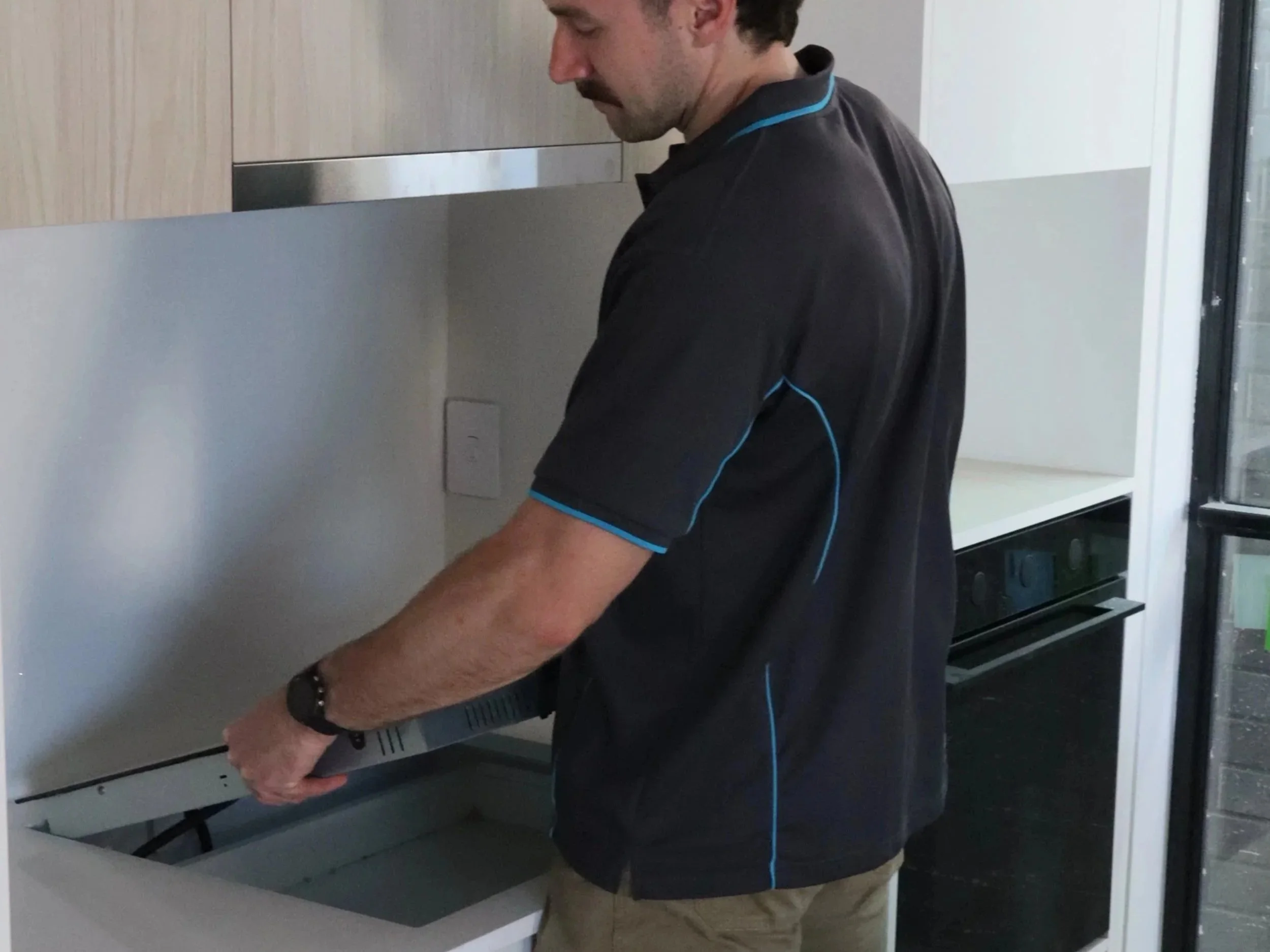 A man installing an induction hotplate in a modern kitchen.
