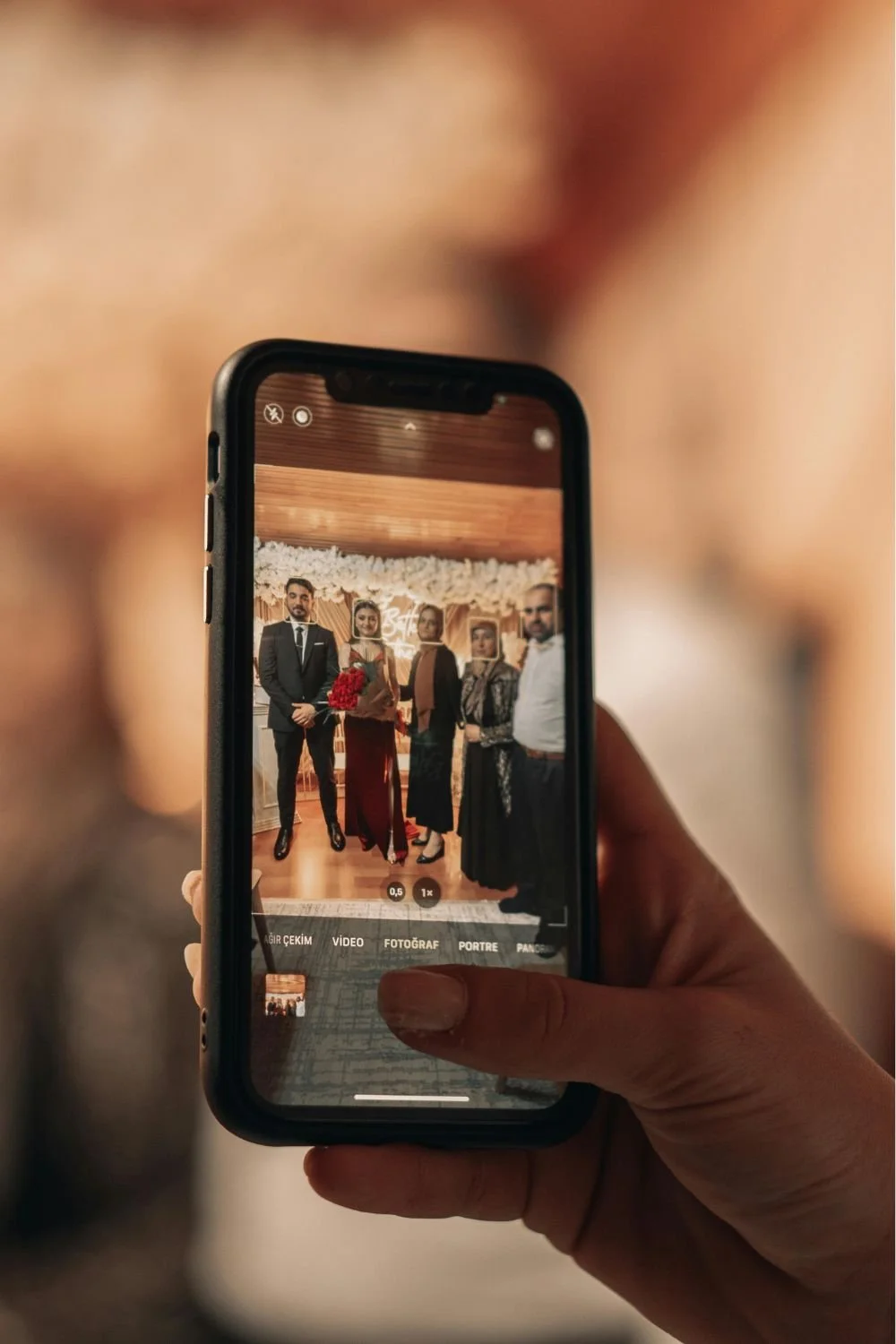 Person photographing group portrait on smartphone at event