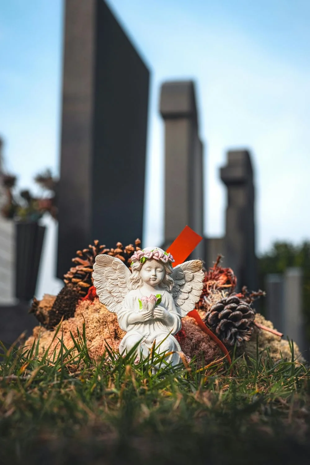 Angel statue beside grave decorations in cemetery setting