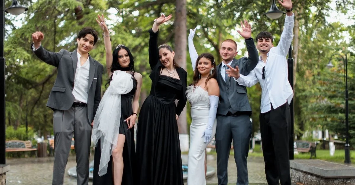 A joyful group of friends celebrating outdoors, dressed elegantly in tuxedos and gowns.