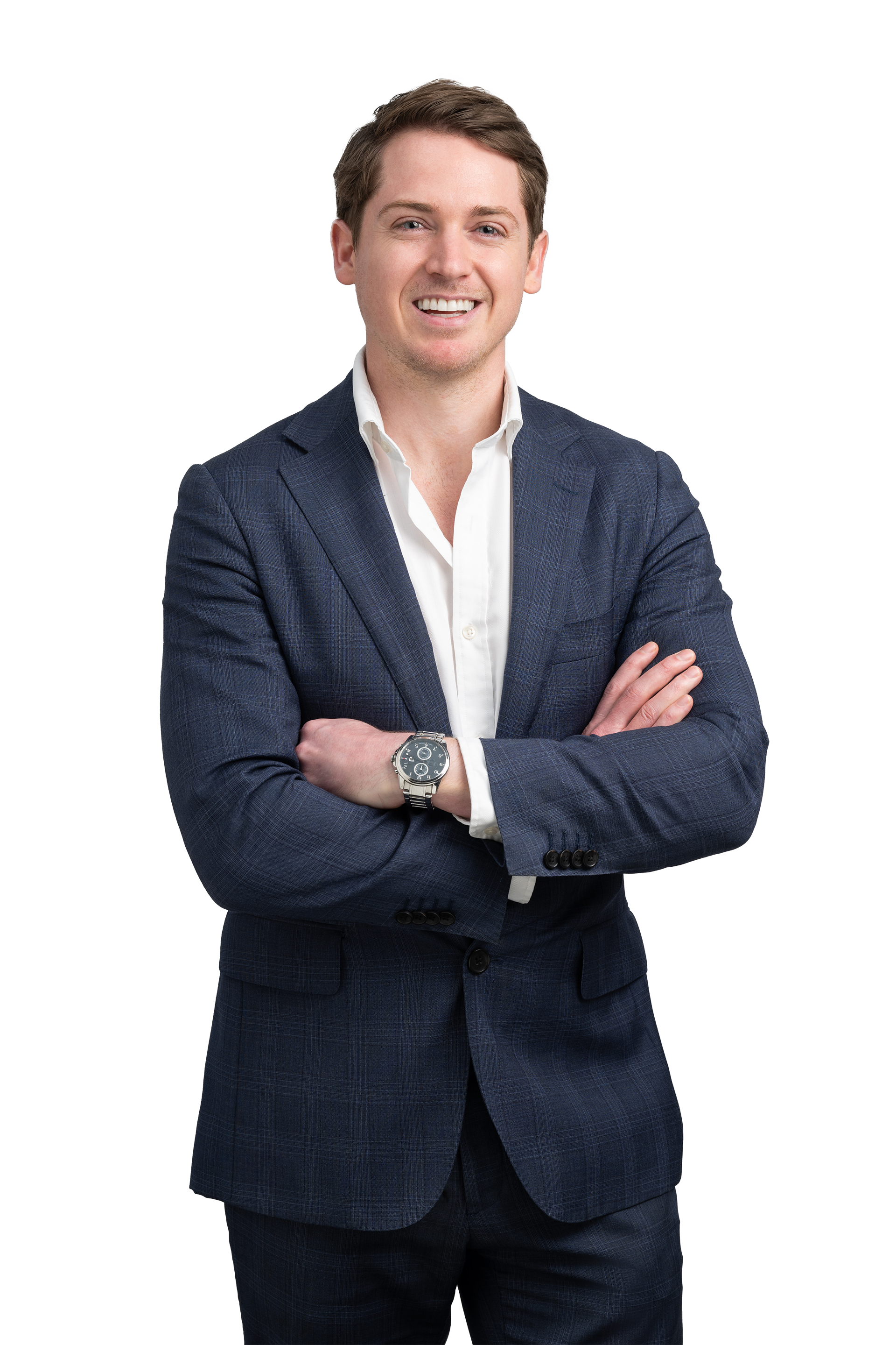 A man with brown hair in a navy checkered blazer, white shirt, and watch, smiling with arms crossed.