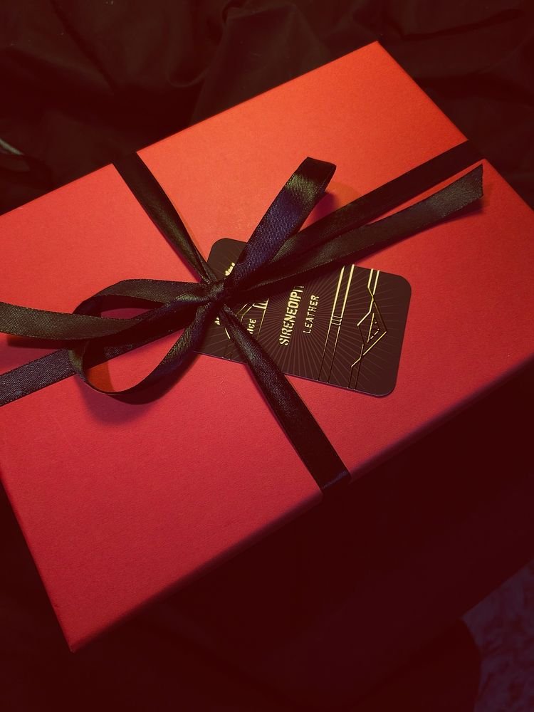 A red gift box tied with a black ribbon and a black tag.