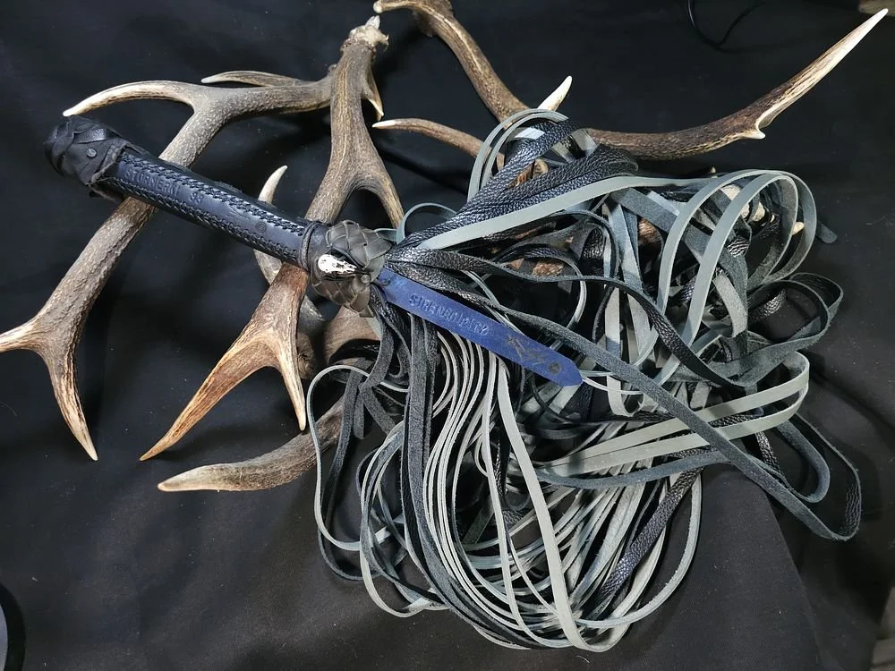 Antlers with a leather handle and tangled rubber or plastic bands on a black surface.
