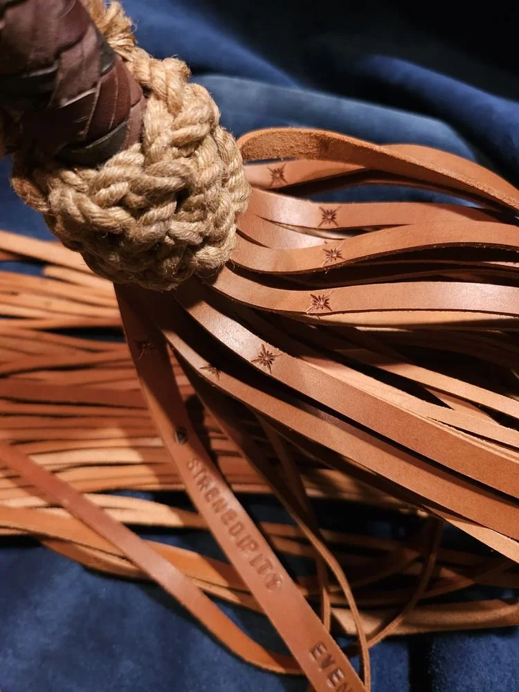 Close-up of a woven straw and leather item, possibly a hat or basket, with braided straw and leather strips with engraved patterns.