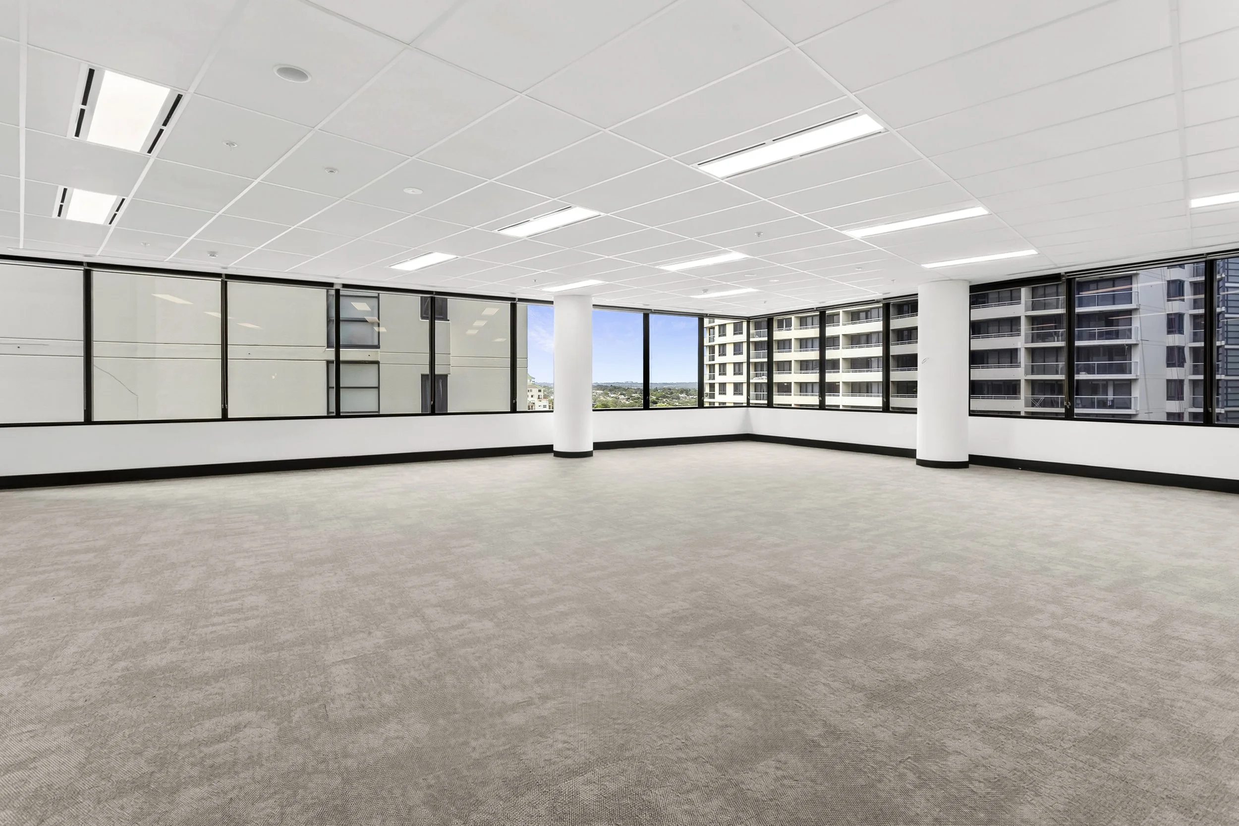 Vacant office space with large windows, white ceiling, beige carpet, and Forum Plaza views outside.