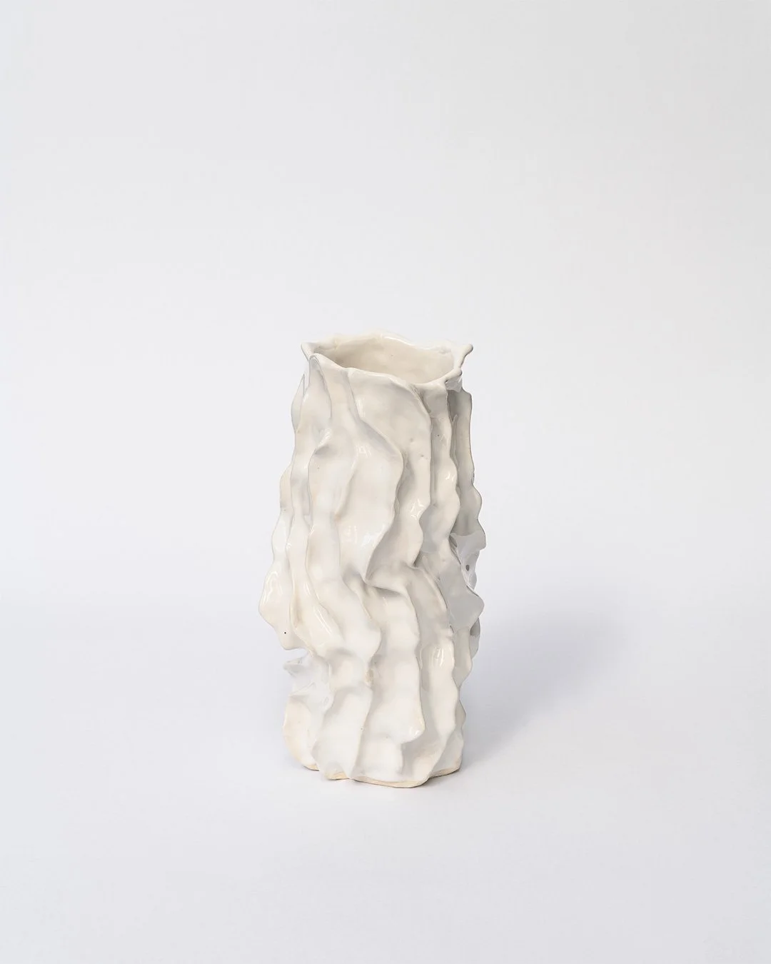 Christchurch, New Zealand artist, Nathan Ingram's tall, white ceramic vase with an irregular, wavy, textured surface set against a plain white background.