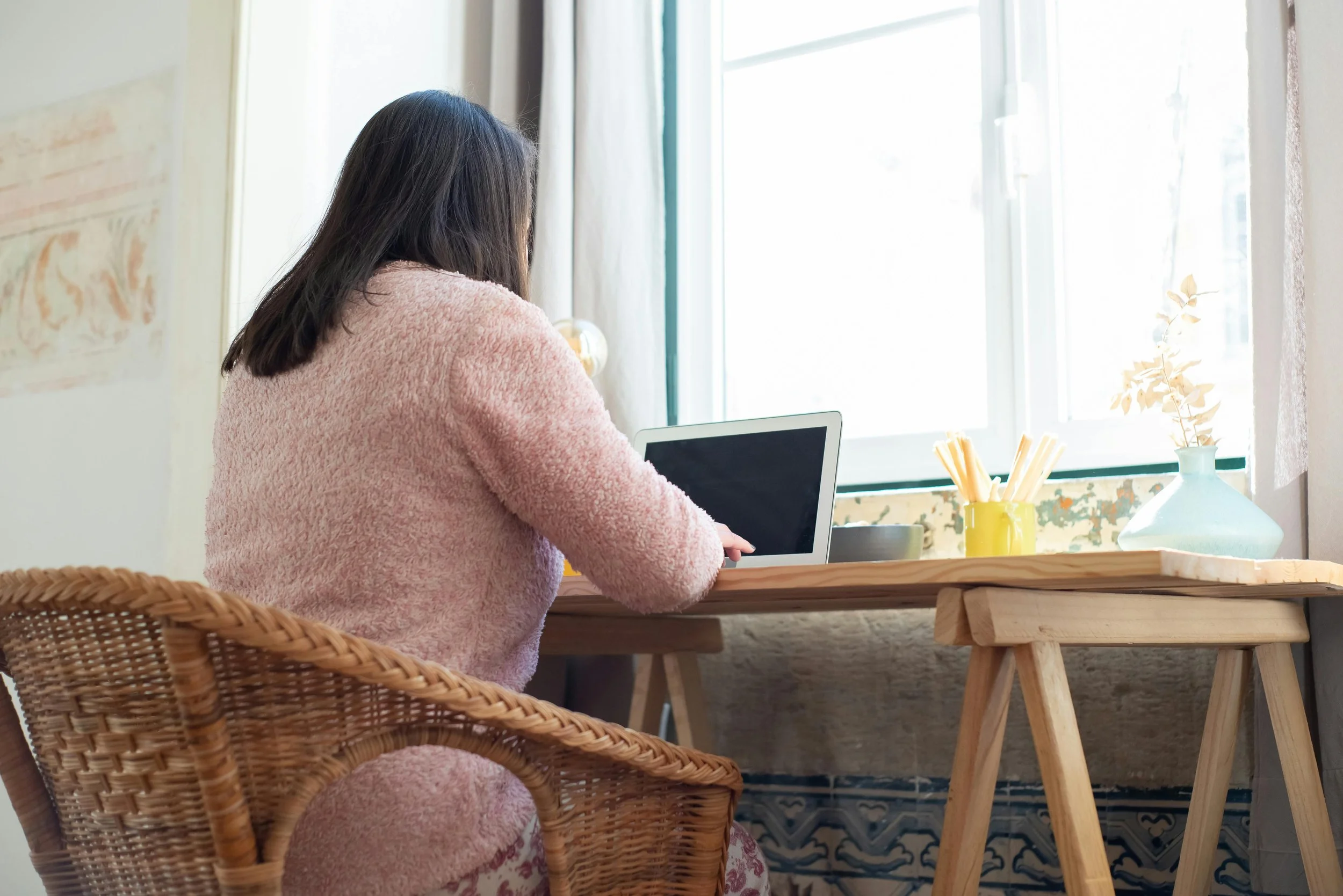 Virtual assistant working remotely from a desk with a bright window.
