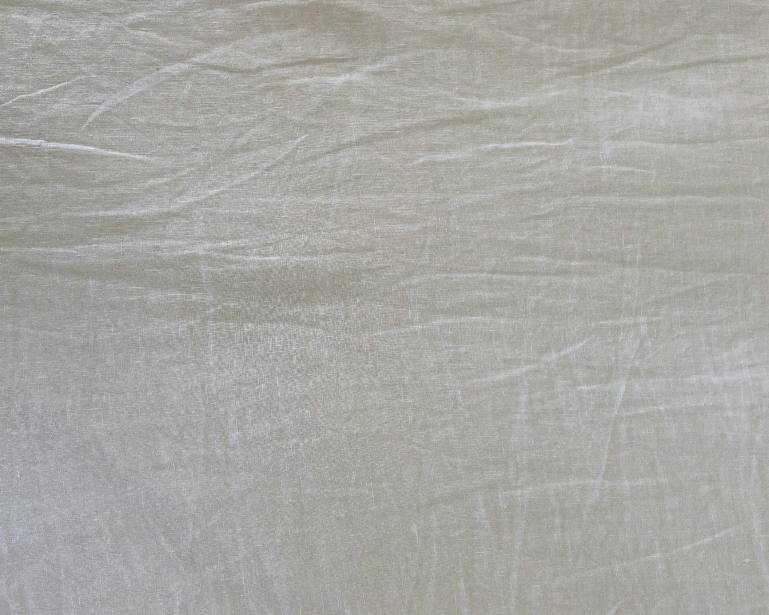 Close-up of a textured, beige fabric surface with visible creases and a slightly shiny finish.