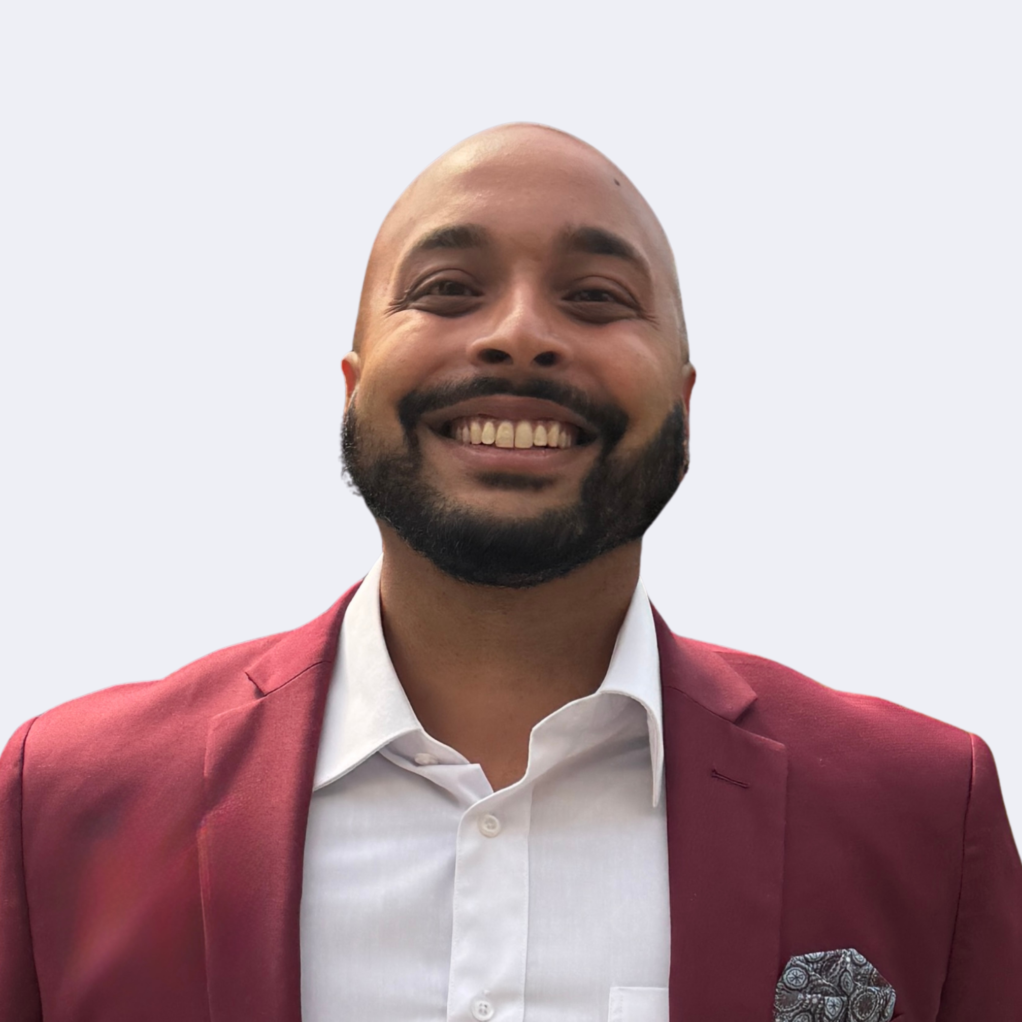 Smiling man wearing a burgundy blazer, white shirt, and a pocket square against a plain background.